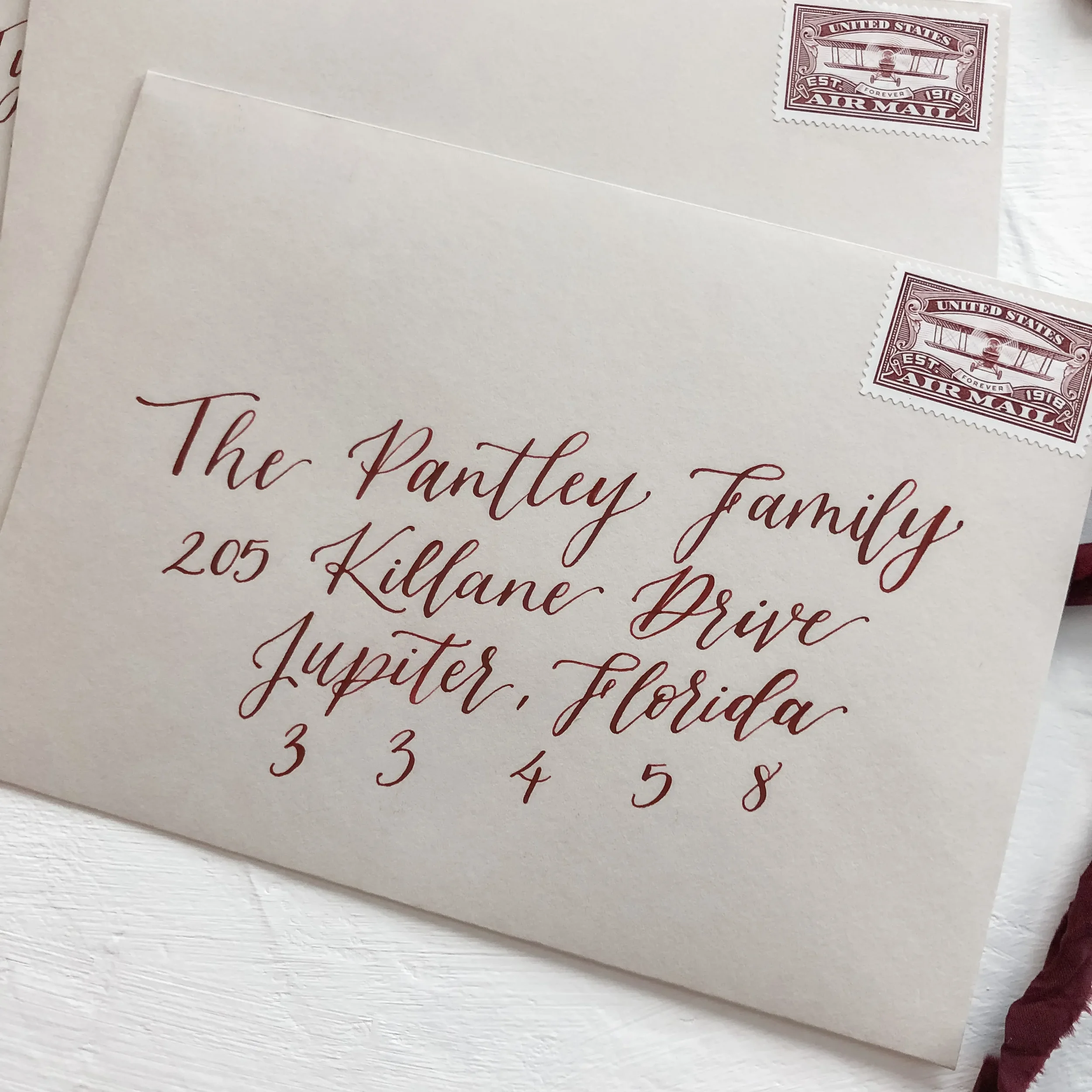 Perfect for an organic autumn or winter celebration, this stack of warm neutral taupe envelopes utilizes rich crimson red ink for guest addressing. Paired with vintage monochromatic postage stamps, this design bridges the gap between old-world romanc