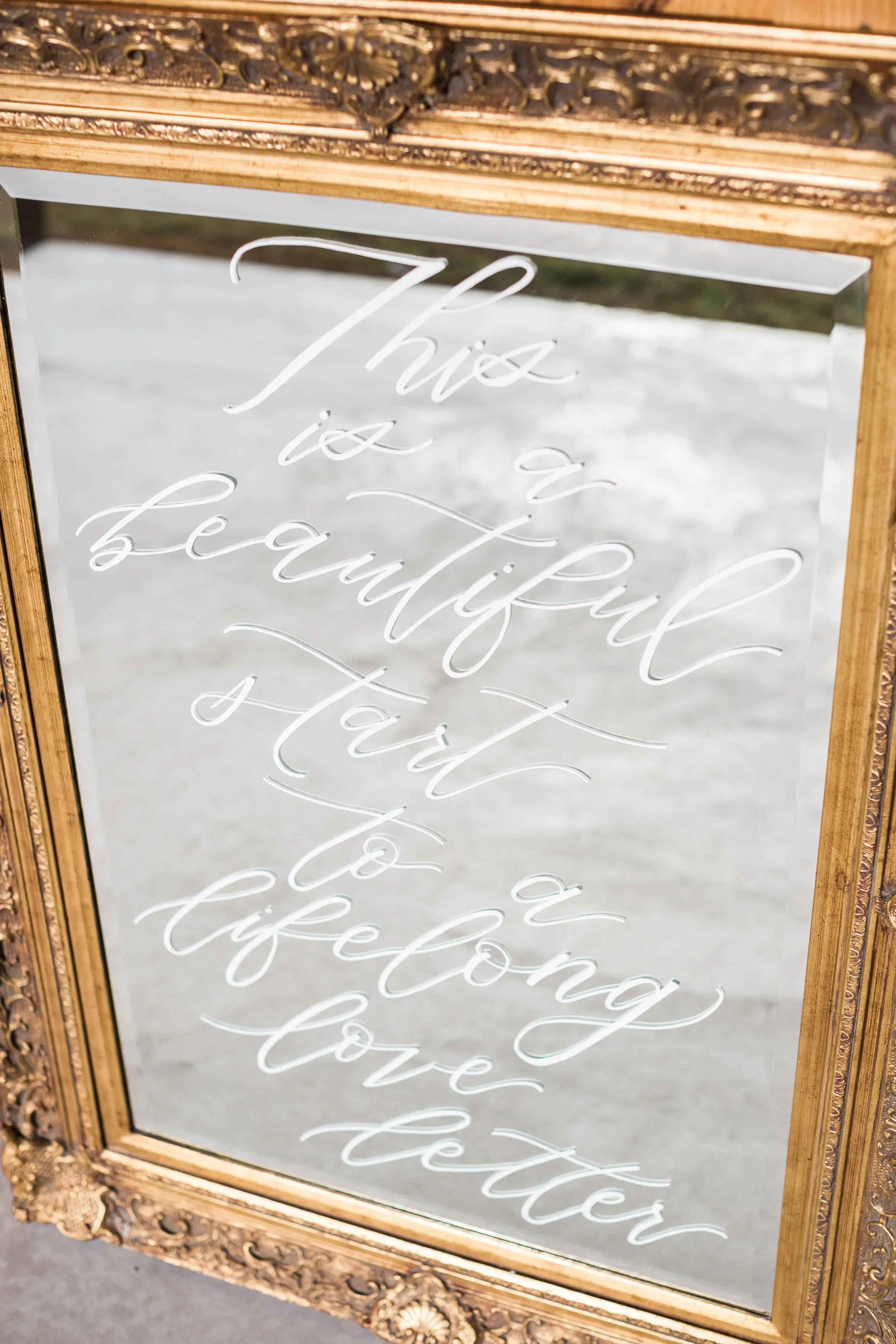 Large ornate gold frame mirror with beveled edges featuring white calligraphy reading "This is a beautiful start to a lifelong love letter".