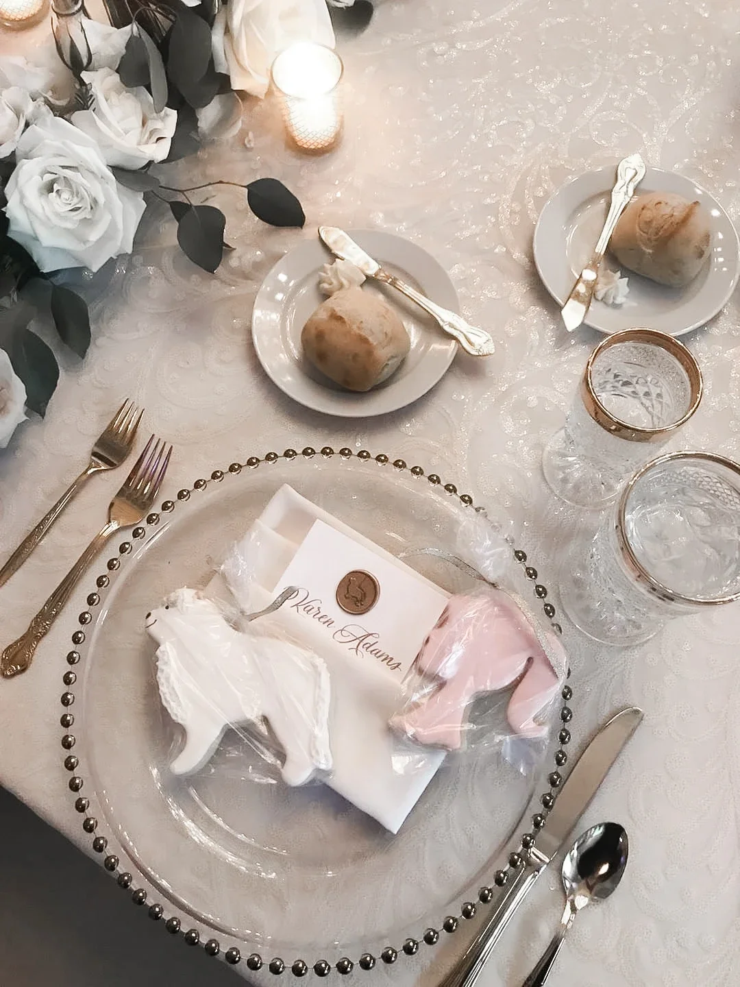 Elegant glass beaded rim charger plate set with a white napkin, custom calligraphed name card, and frosted cookie favors.