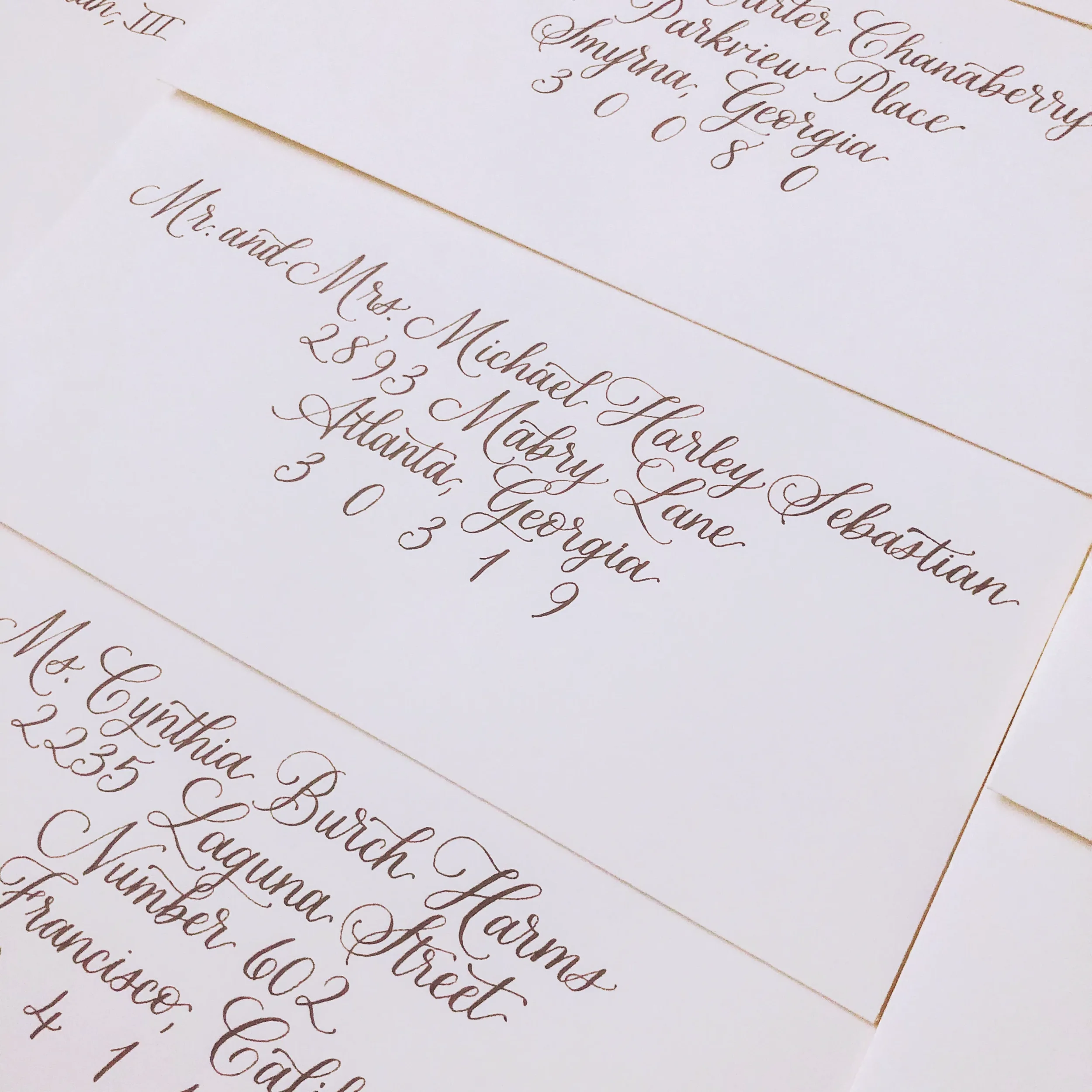 Close-up of elegant cream colored wedding envelopes addressed in a flawless walnut brown script font.