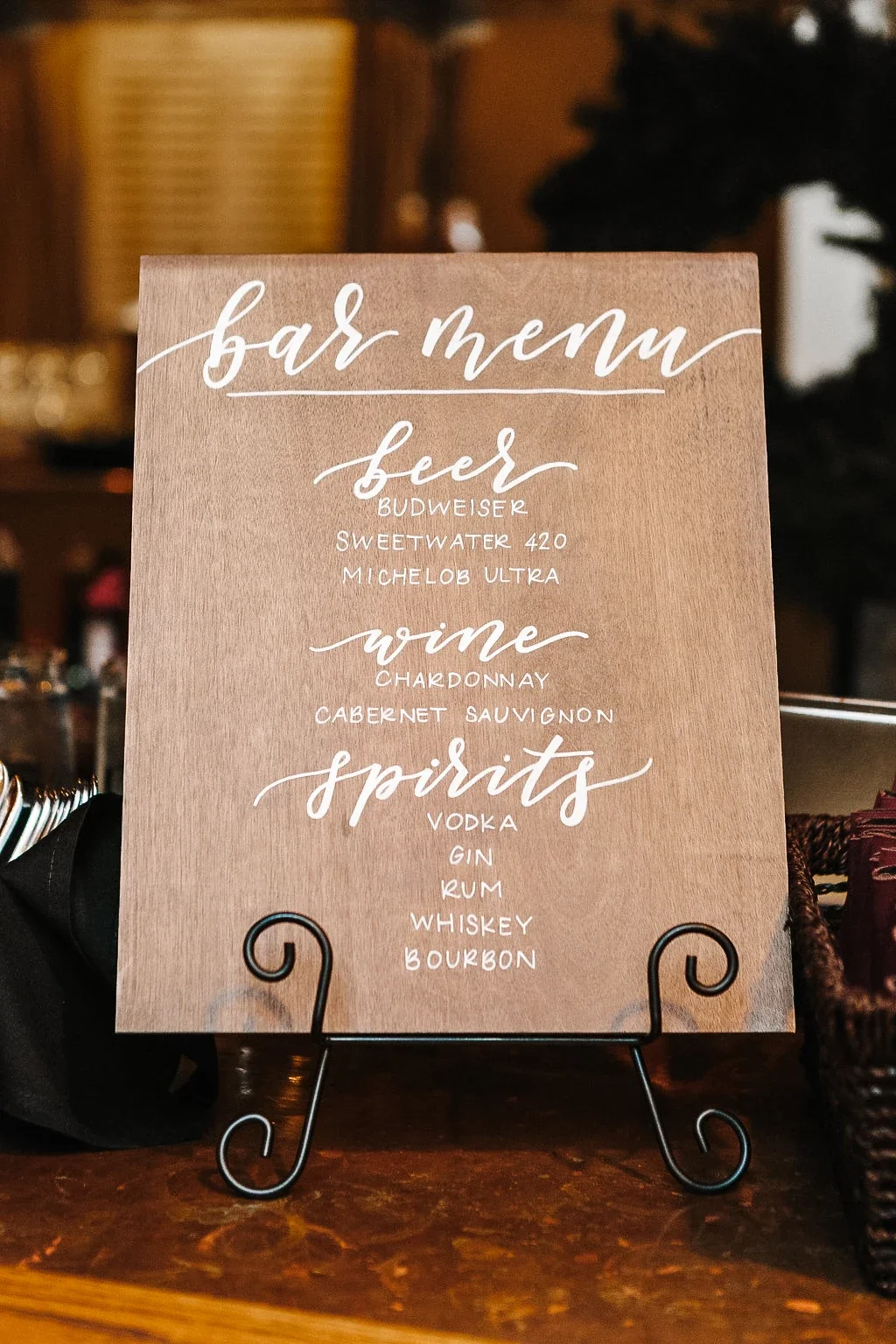 Stained wood bar menu wedding sign listing beer, wine, and spirits options.