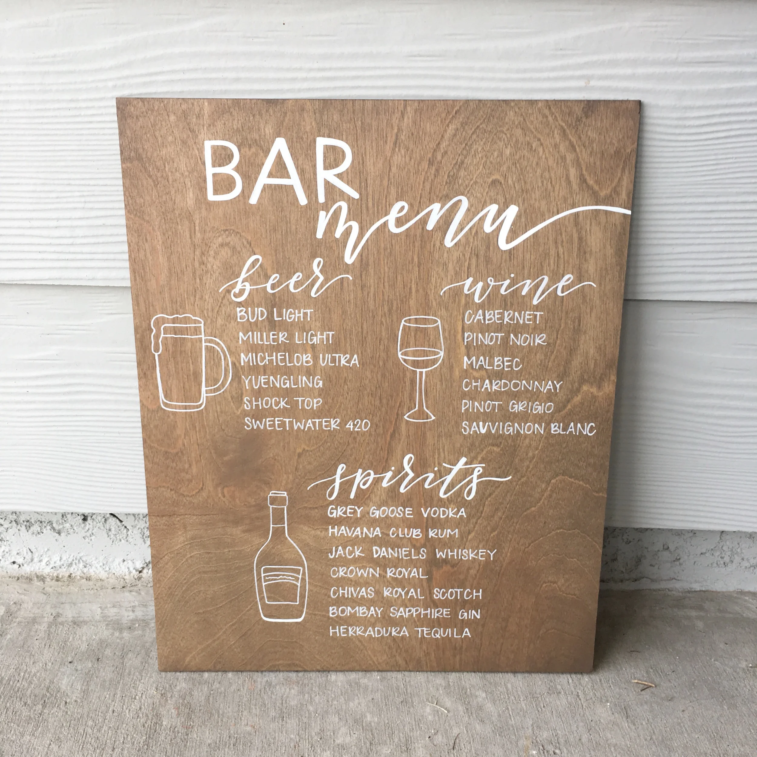 Stained wood bar menu sign listing beer, wine, and spirits options with simple white line illustrations.