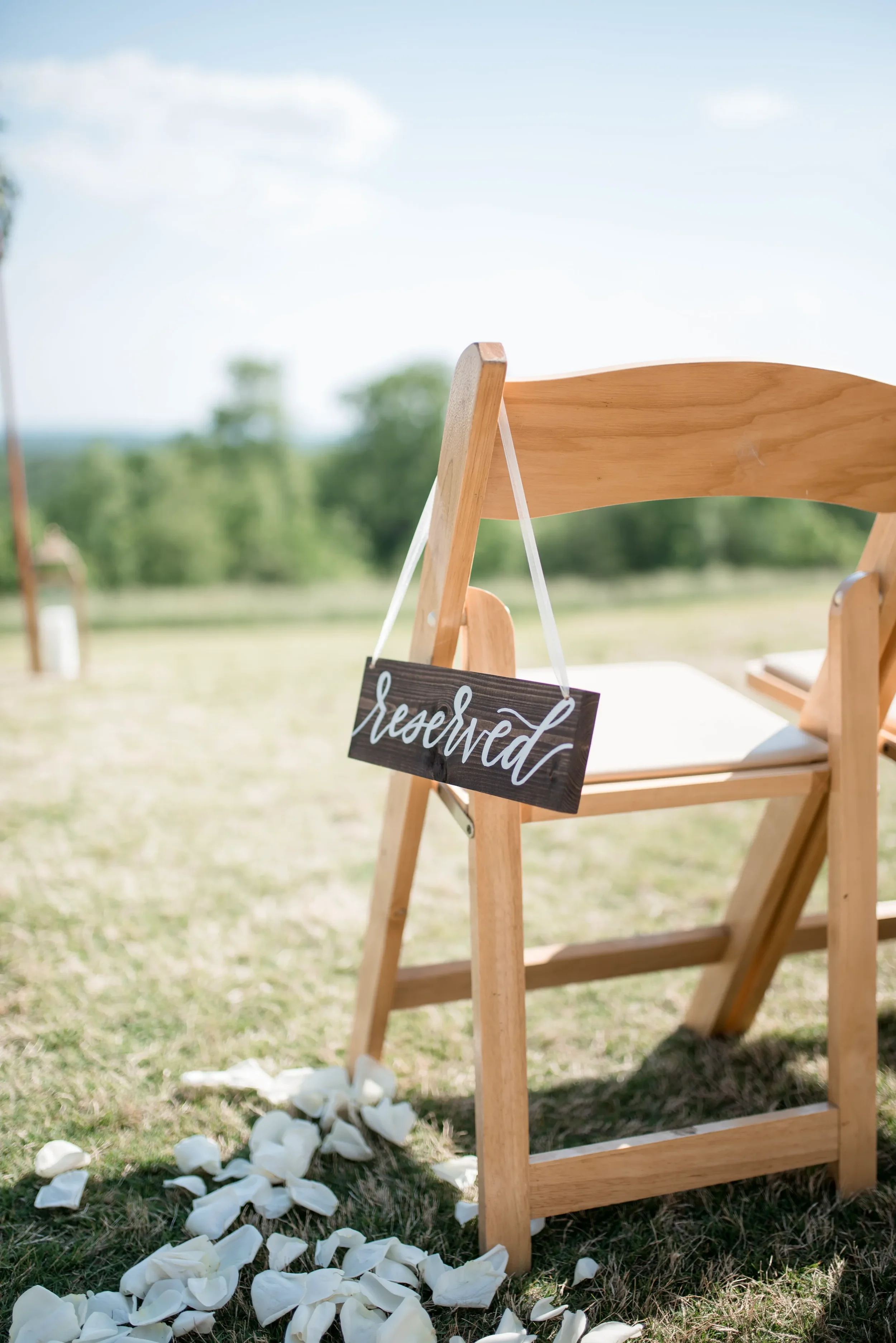 Hand lettered wooden reserved chair sign with white calligraphy for outdoor Georgia wedding.
