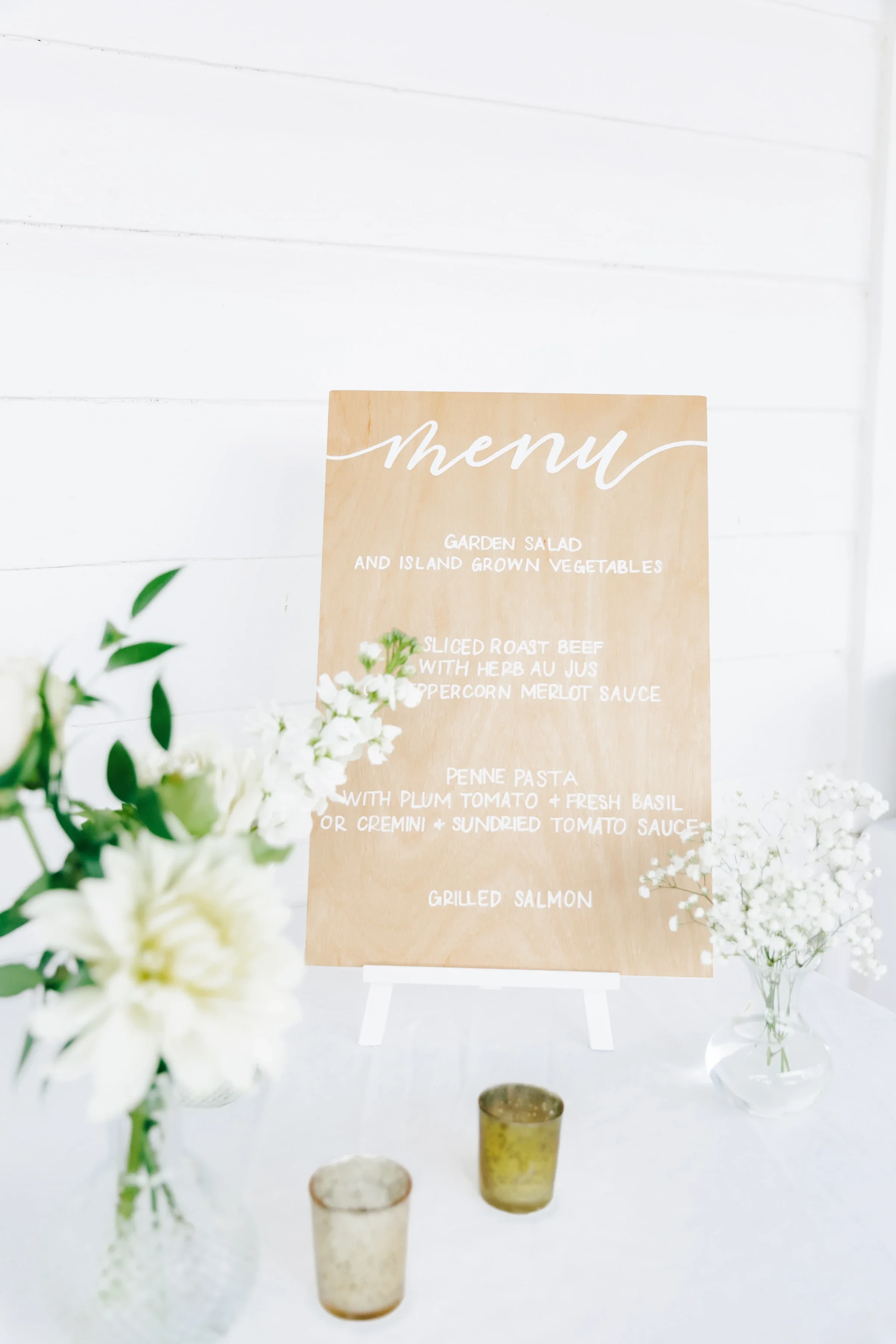 Light natural wood board with hand-lettered white script listing dinner menu options like garden salad, roast beef, and salmon.