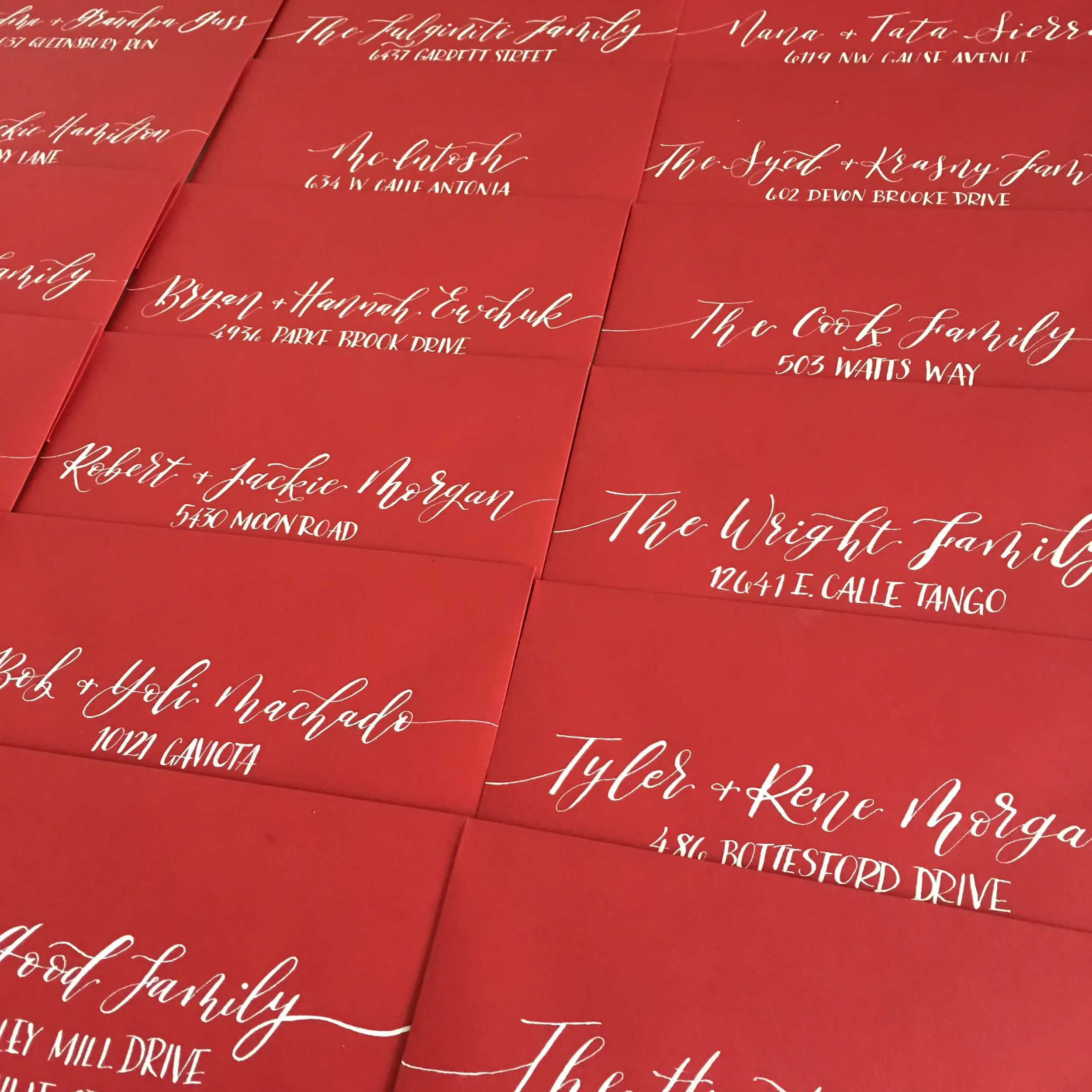 Bold red acrylic wedding invitation with white calligraphy addressing.