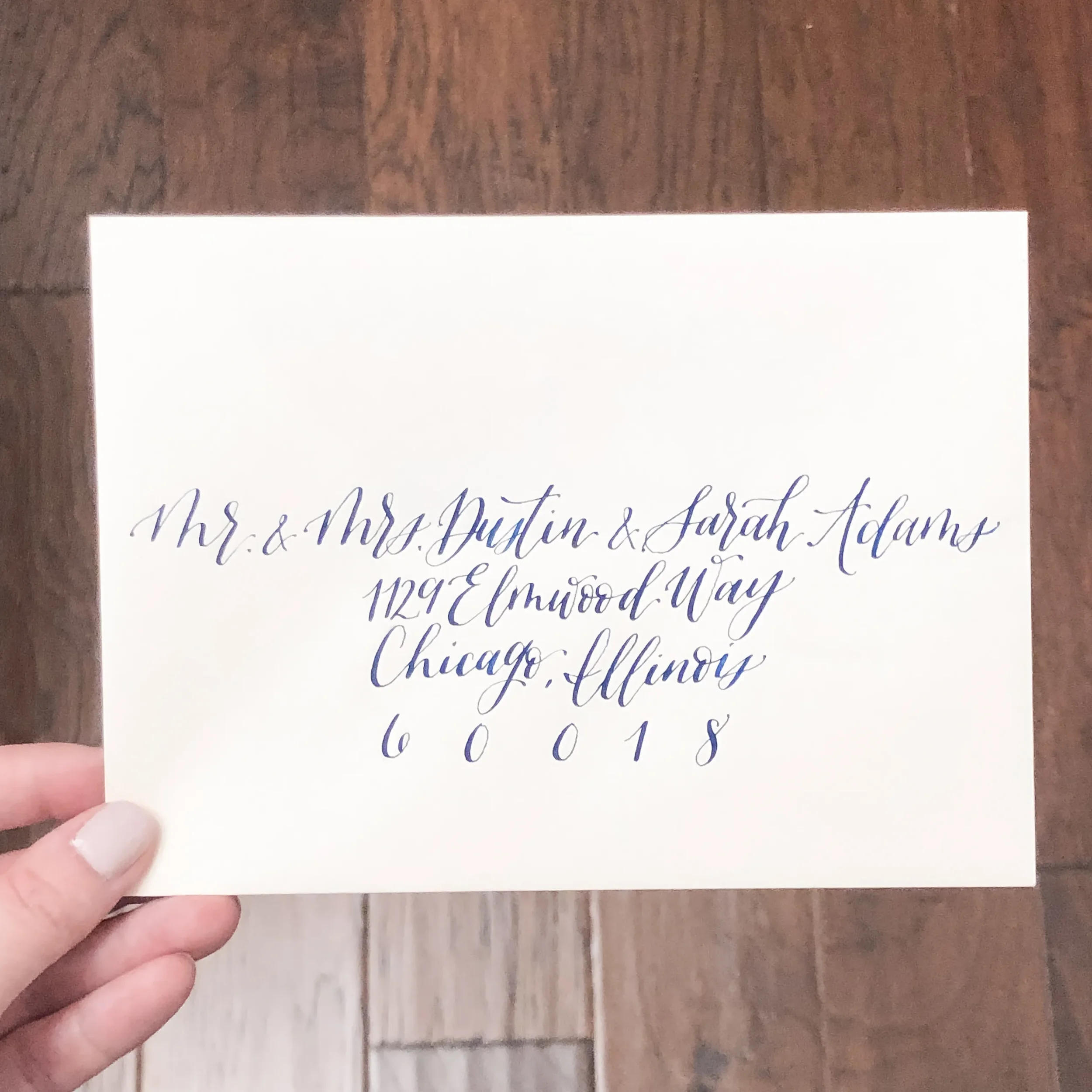 White wedding guest envelope in navy blue calligraphy ink.