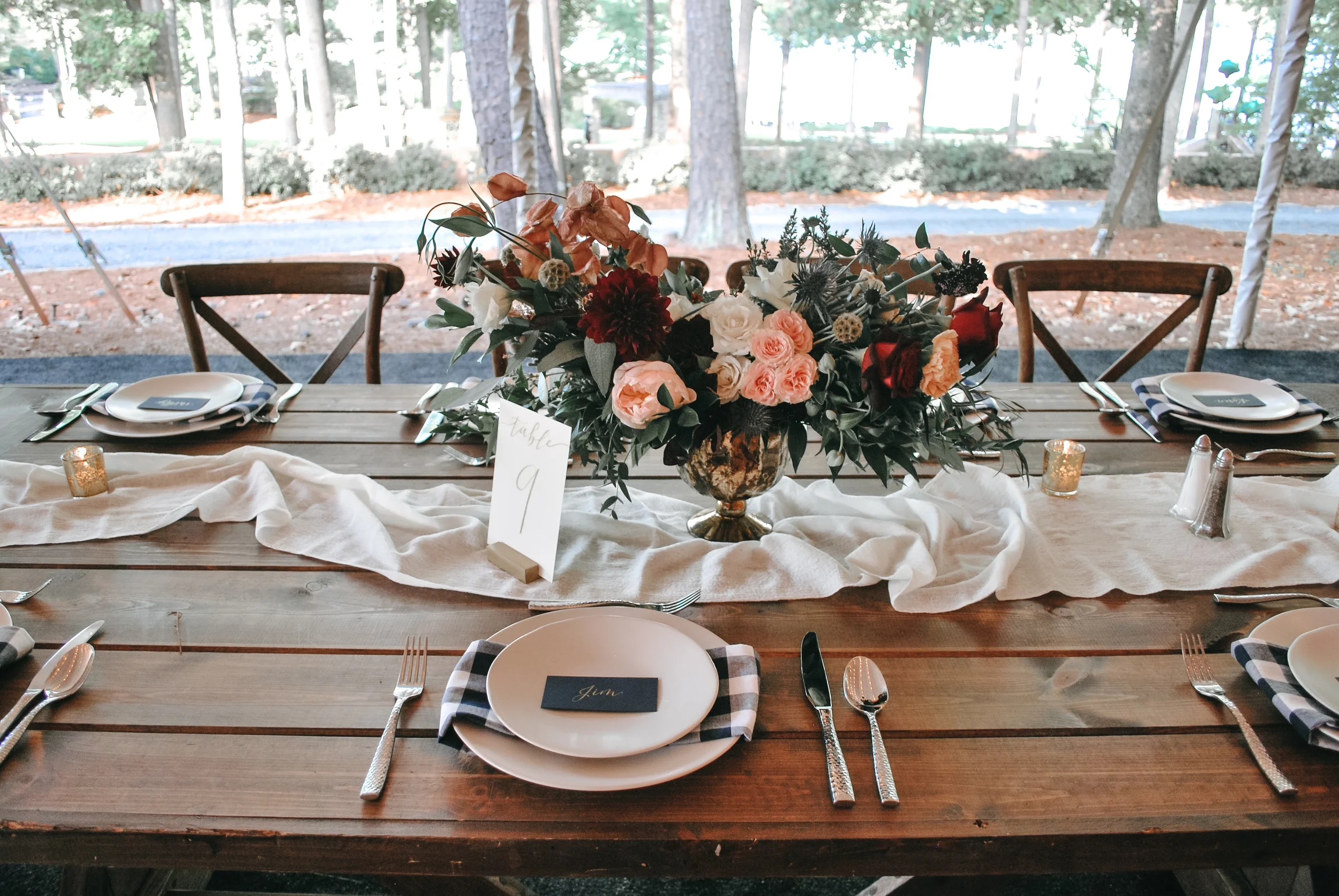 Calligraphy table numbers on a wood stand for a simple rustic outdoor wedding reception.