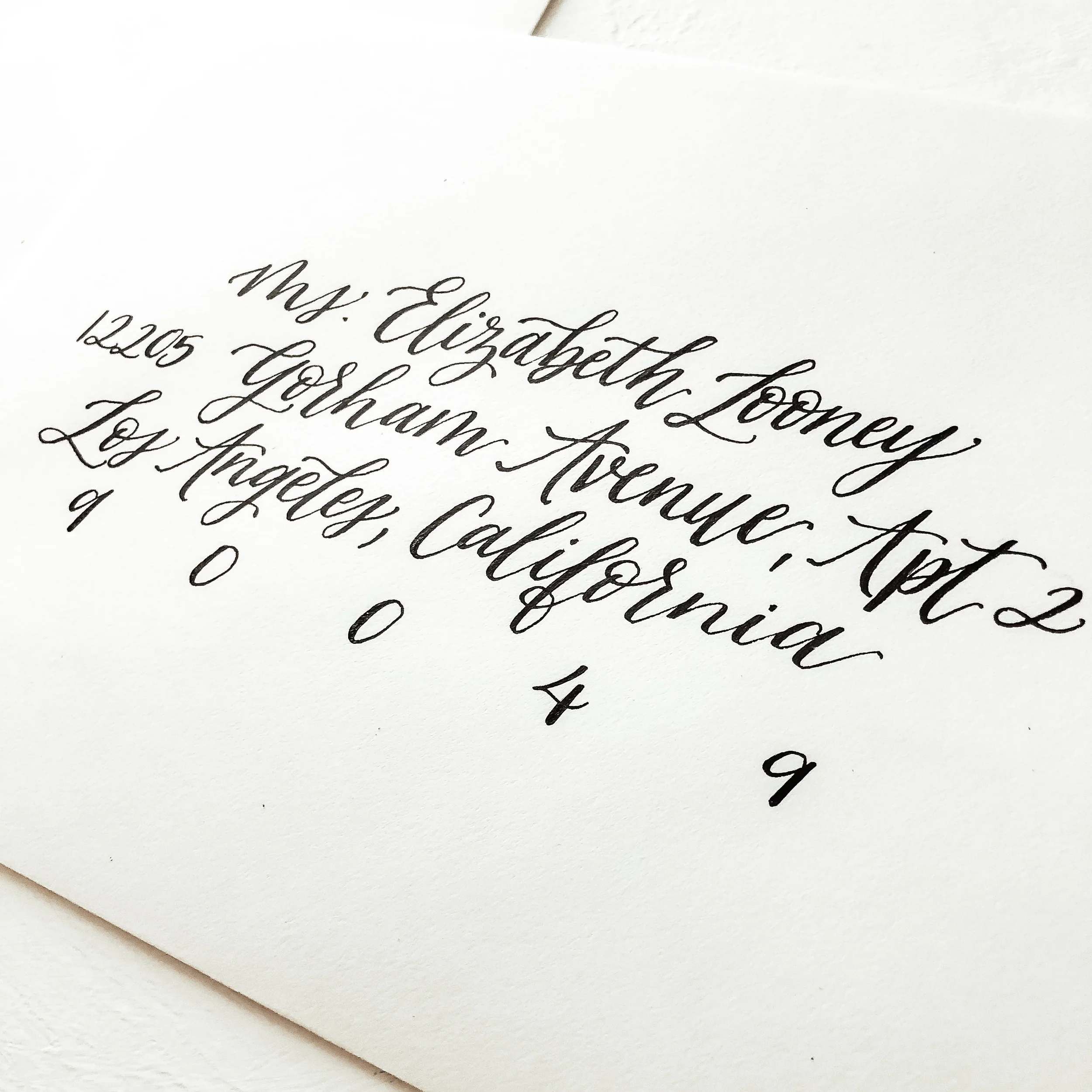 Traditional black ink modern calligraphy on a clean white guest envelope for wedding guest.