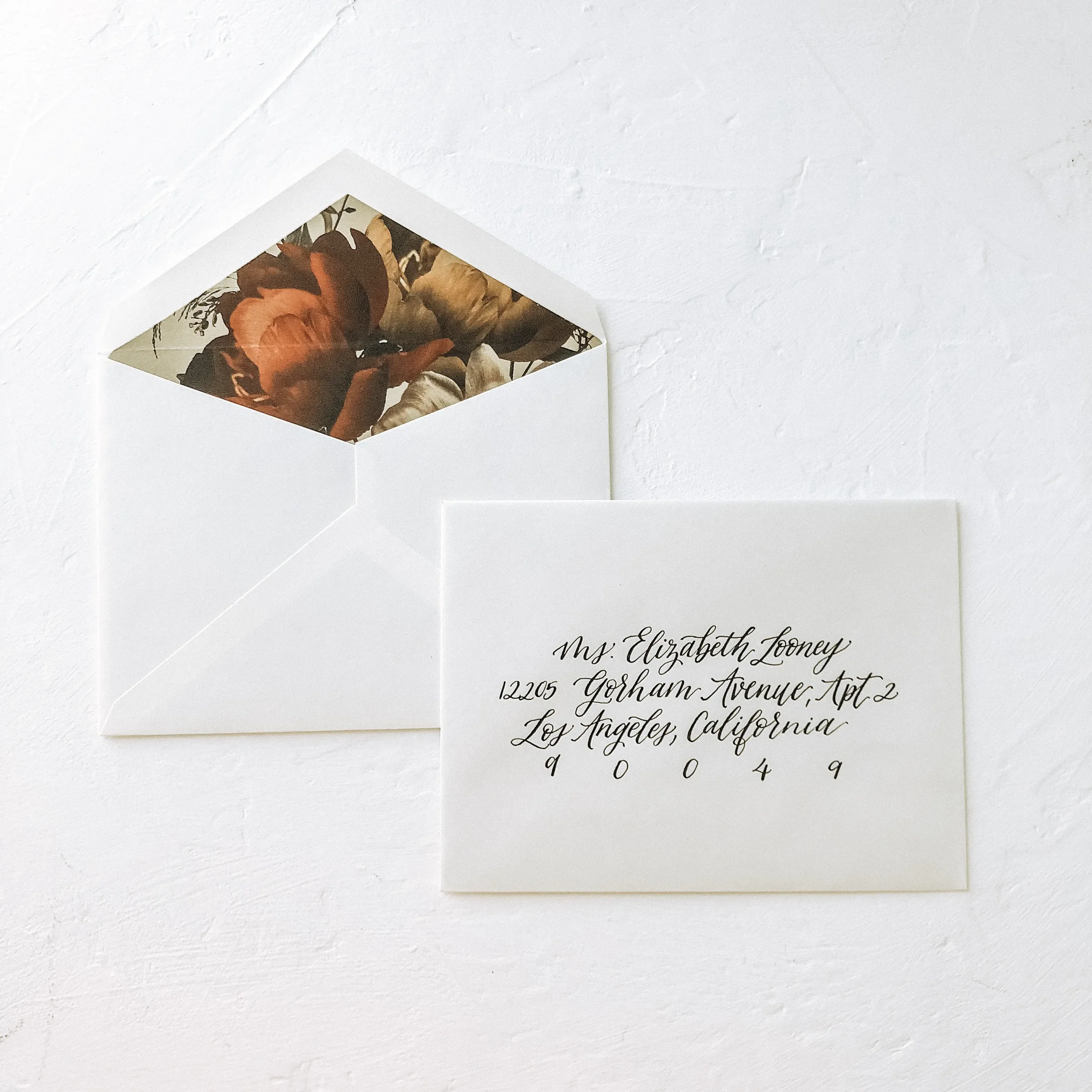 Cream invitation envelope opened to reveal a rich dark moody floral watercolor envelope liner.