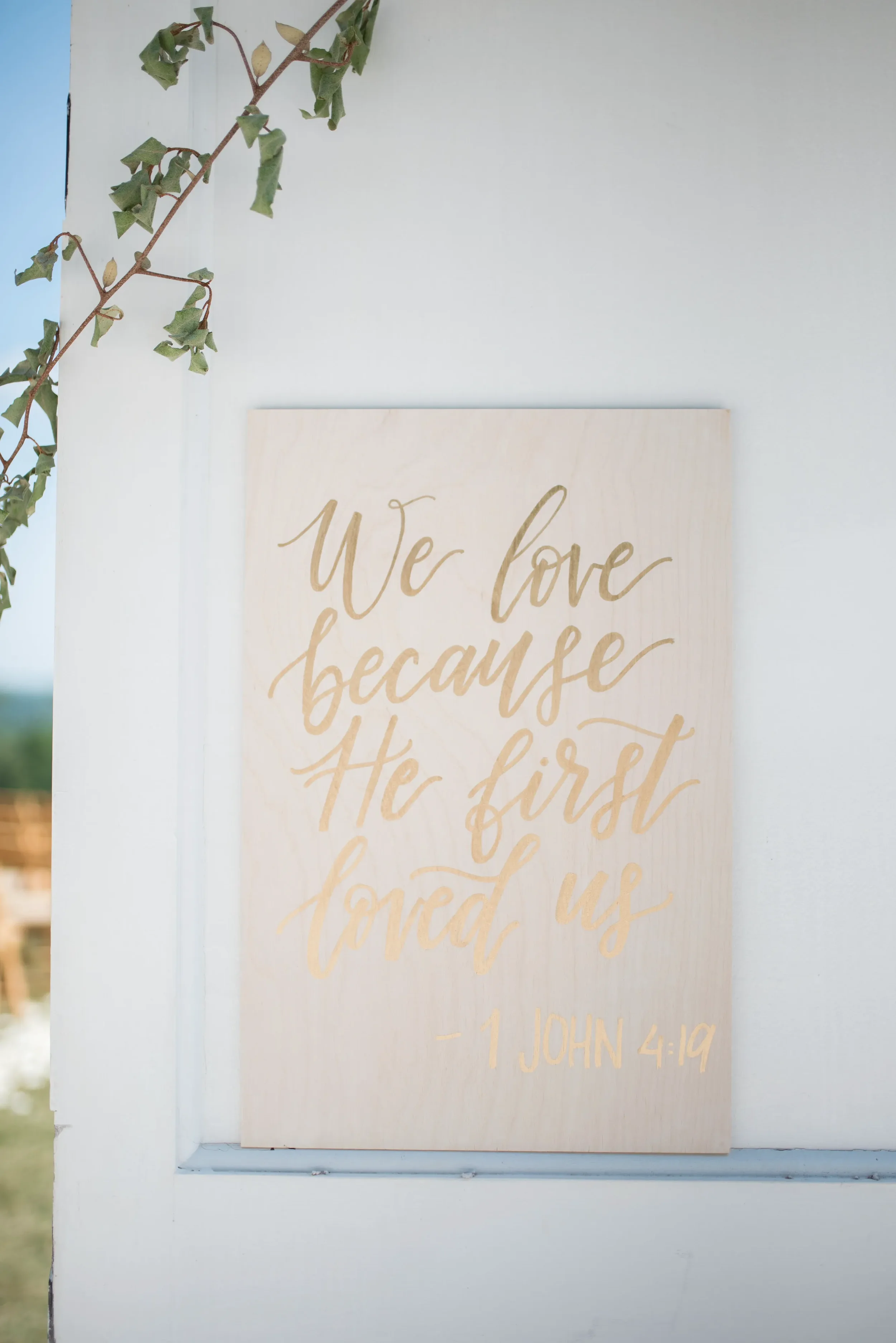 Gold hand lettered white wood bible verse sign for outdoor Georgia wedding.