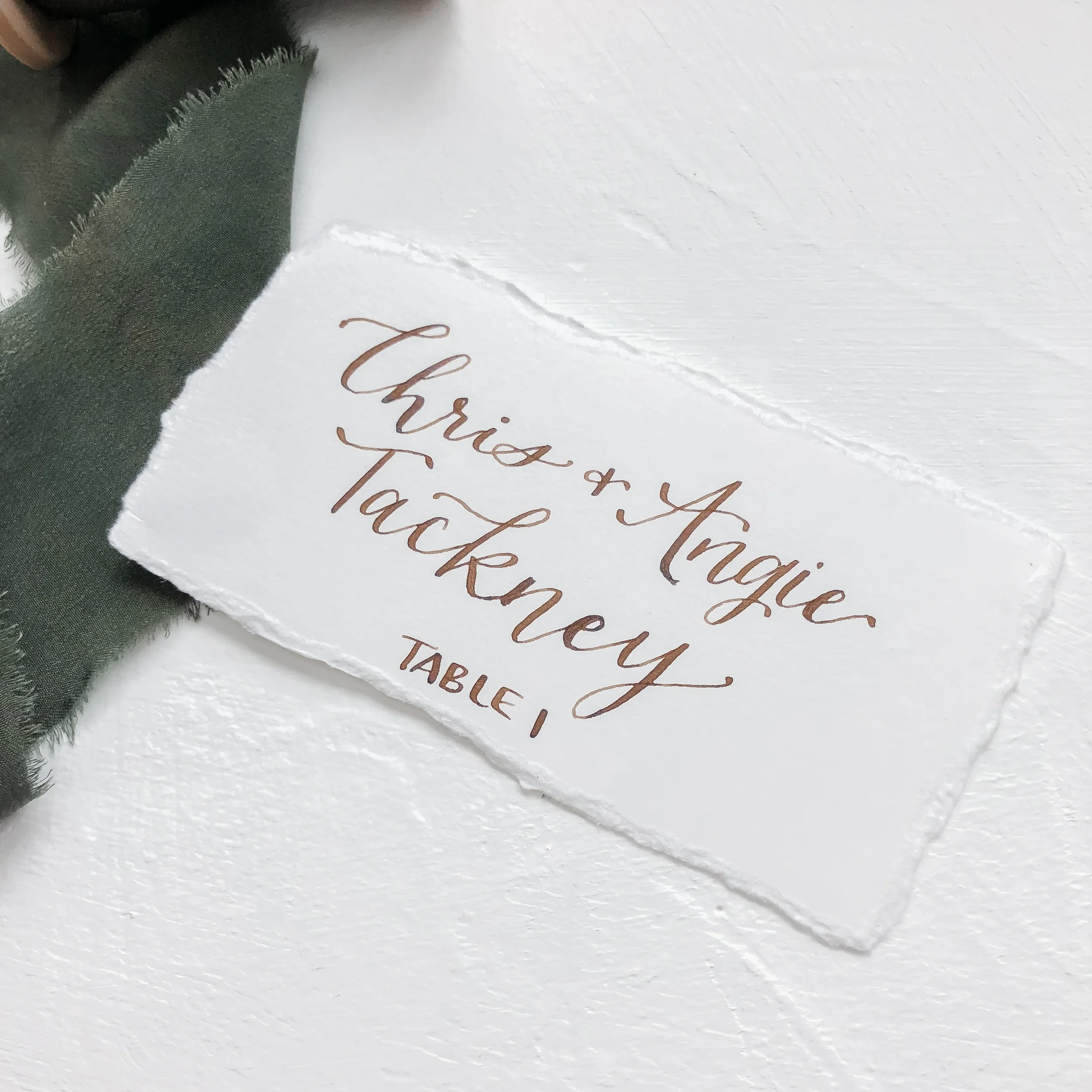 White torn edge escort card with walnut brown calligraphy ink.