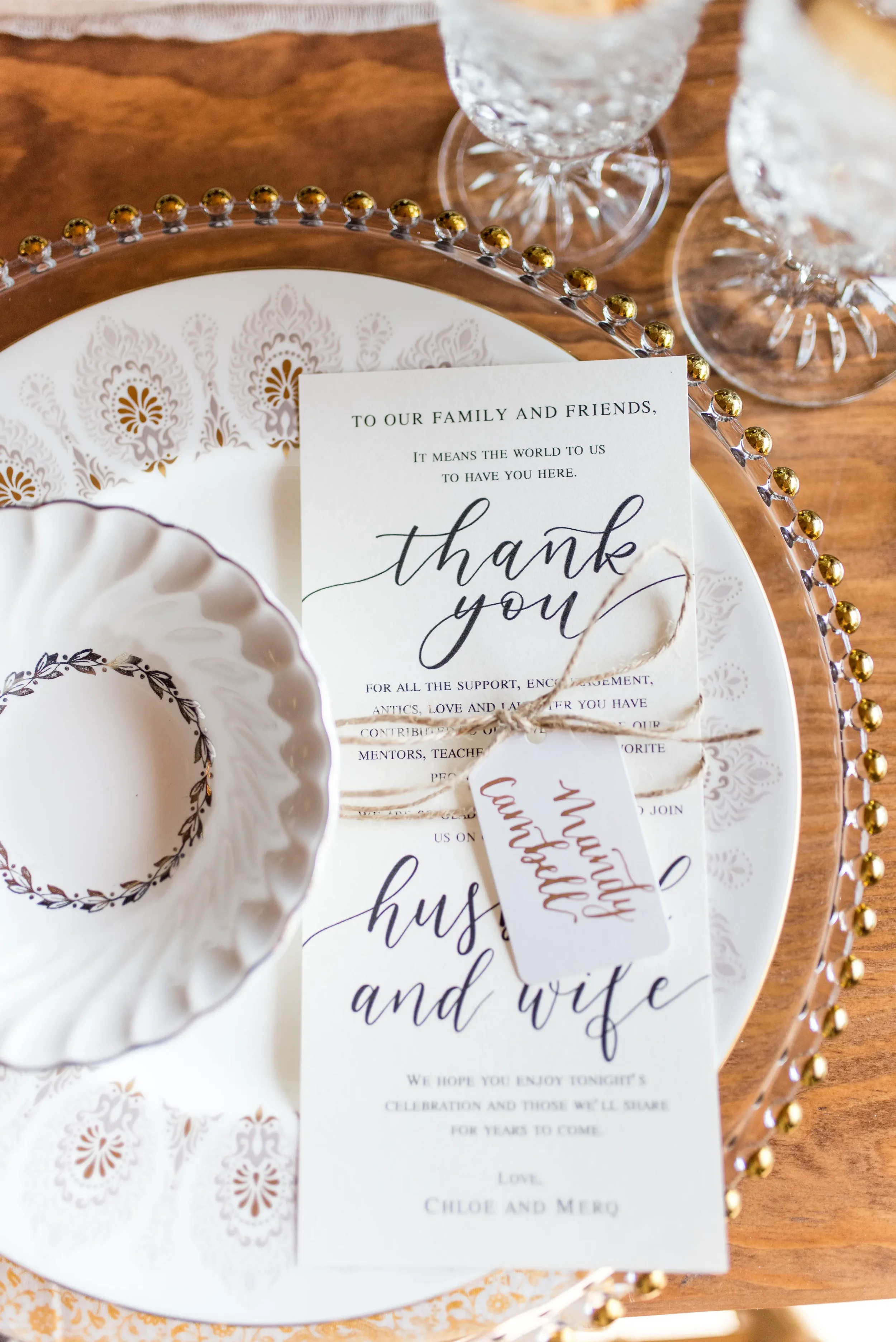Vintage porcelain wedding place setting with a gold beaded charger plate and calligraphed thank you card.