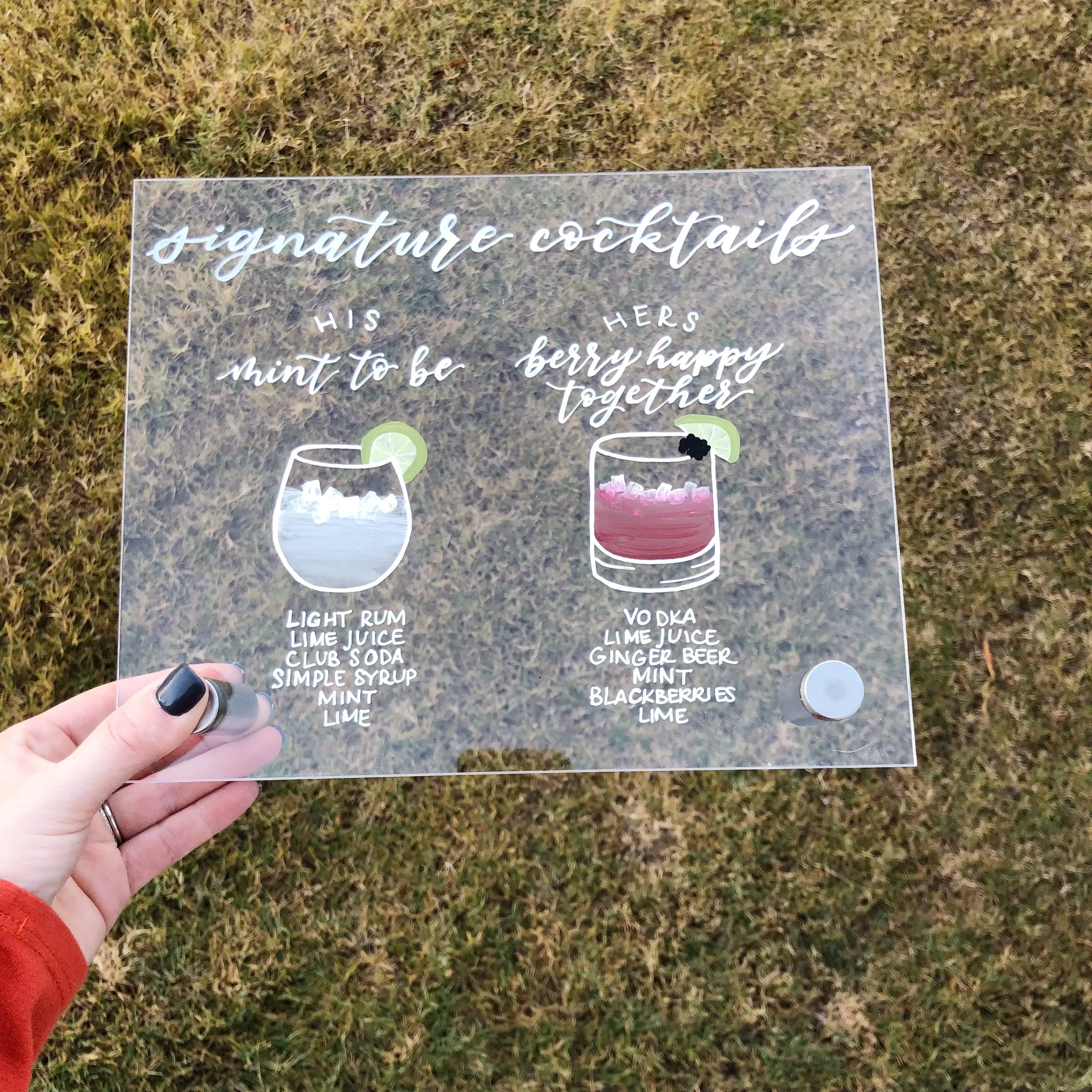 Clear acrylic signature cocktails wedding sign featuring detailed hand-painted drink illustrations.