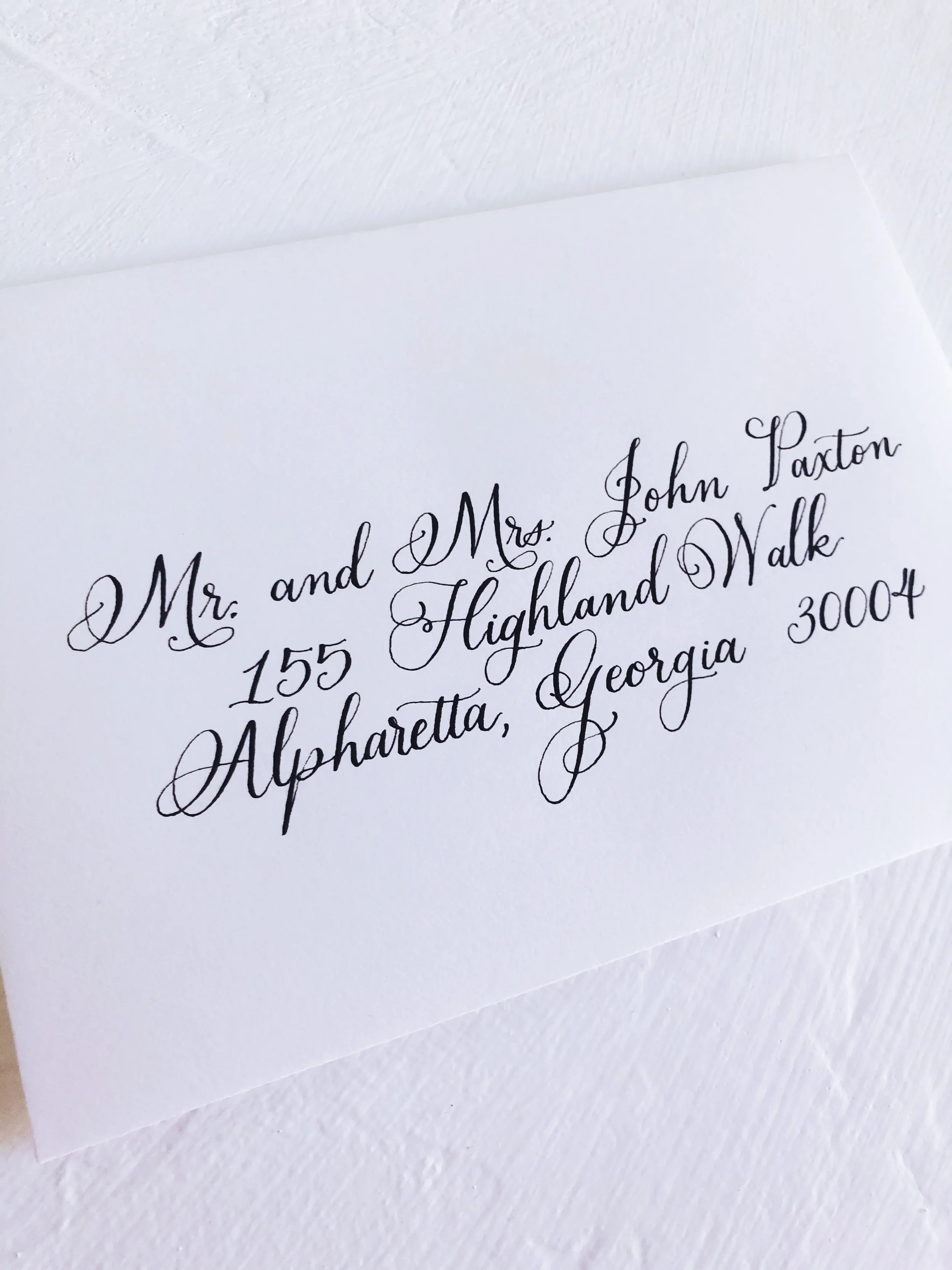 Set an elegant tone for your event right from the mailbox with classic black ink calligraphy envelope addressing. Hand-lettered in sweeping, formal script on crisp white cotton cardstock, this traditional addressing style brings heirloom legibility a