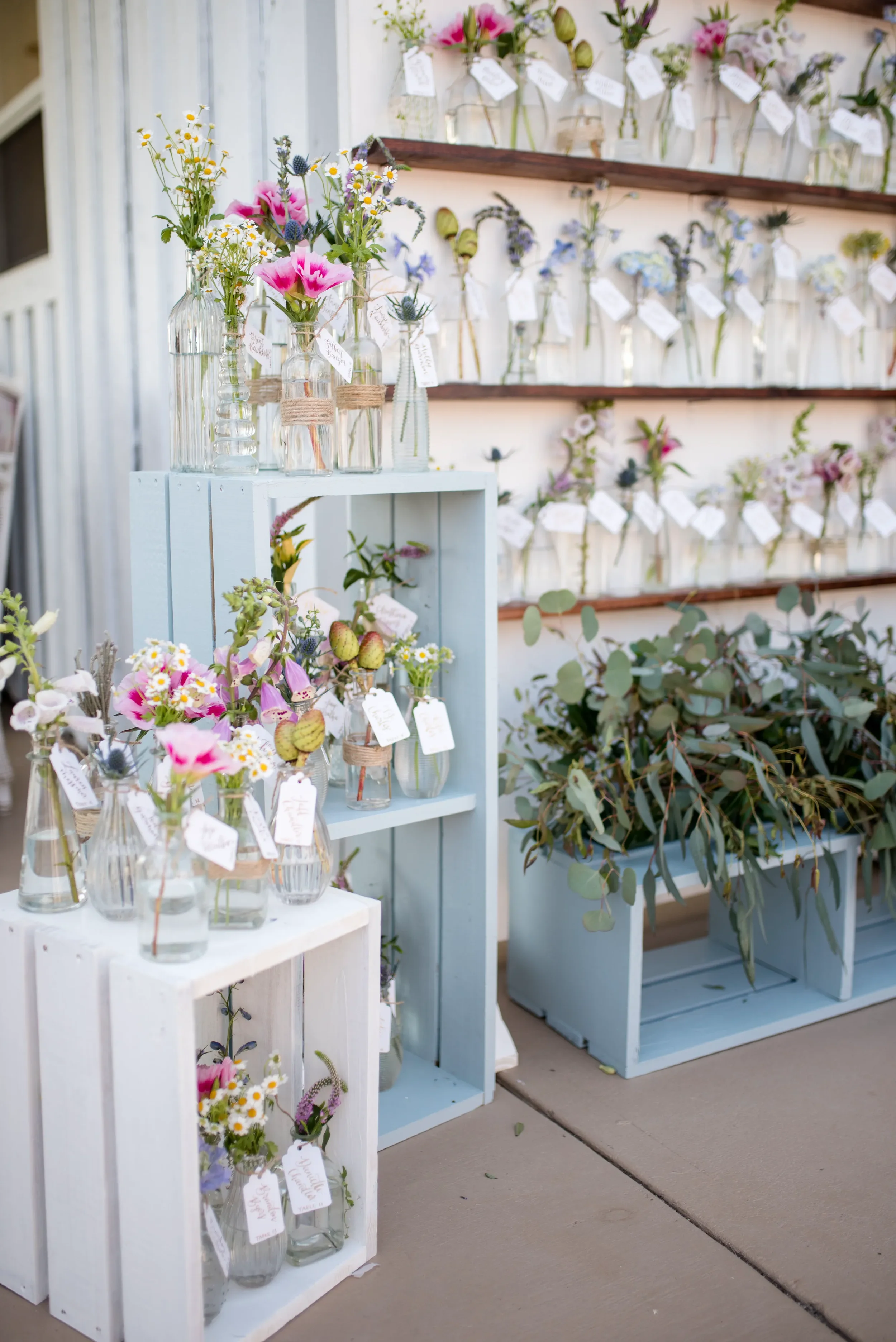 Elevate your reception decor using delicate, custom calligraphy tags styled on fresh floral bud vases. Perfect for an outdoor or garden celebration, this unique seating assignment idea seamlessly blends elegant stationery with organic design.