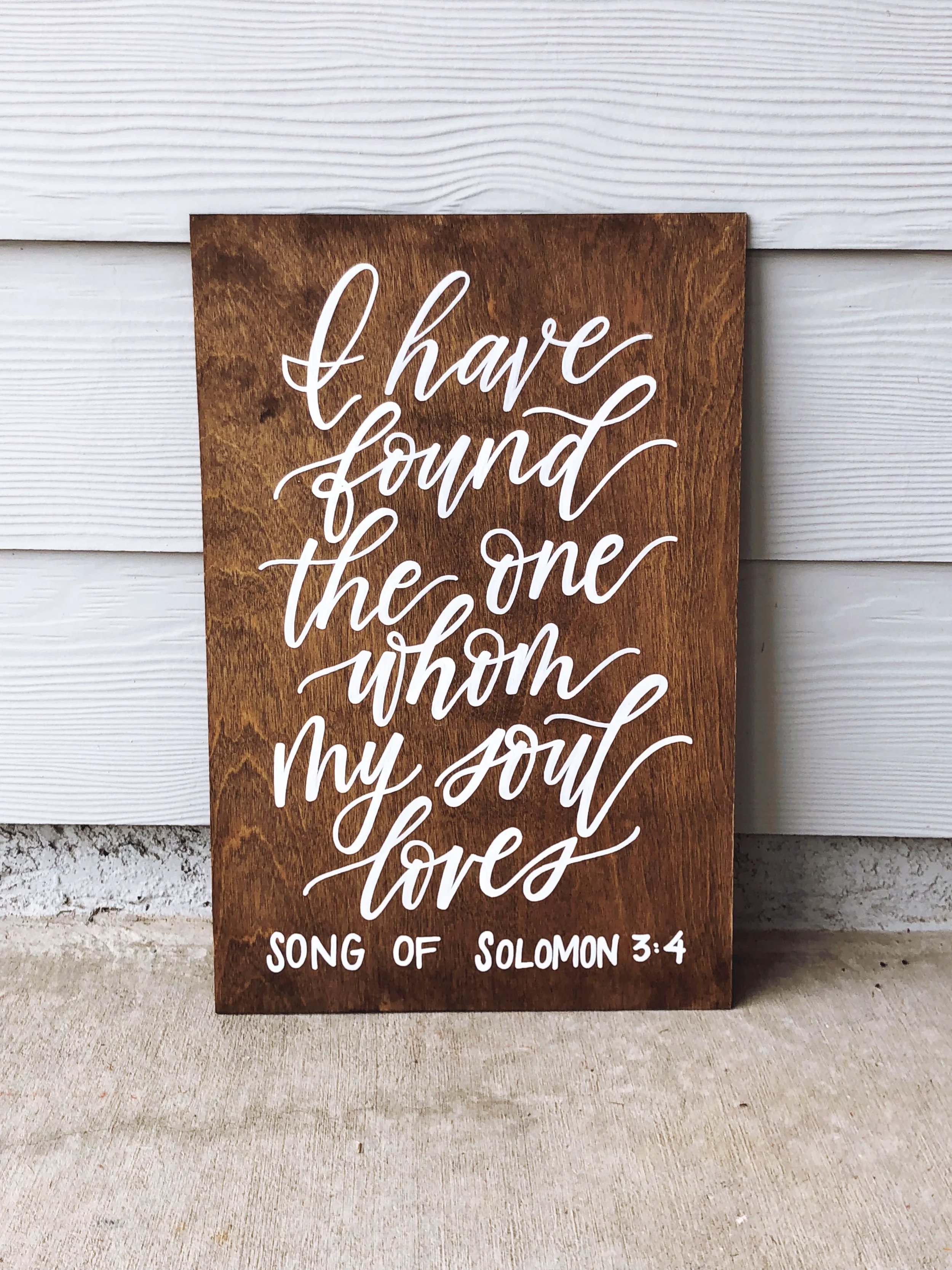Infuse meaningful, faith-filled romance into your ceremony with a hand-lettered Scripture wood sign. Stained in a warm tone and written in white calligraphy script, this "Song of Solomon 3:4" display makes a cherished keepsake to hang in your home af