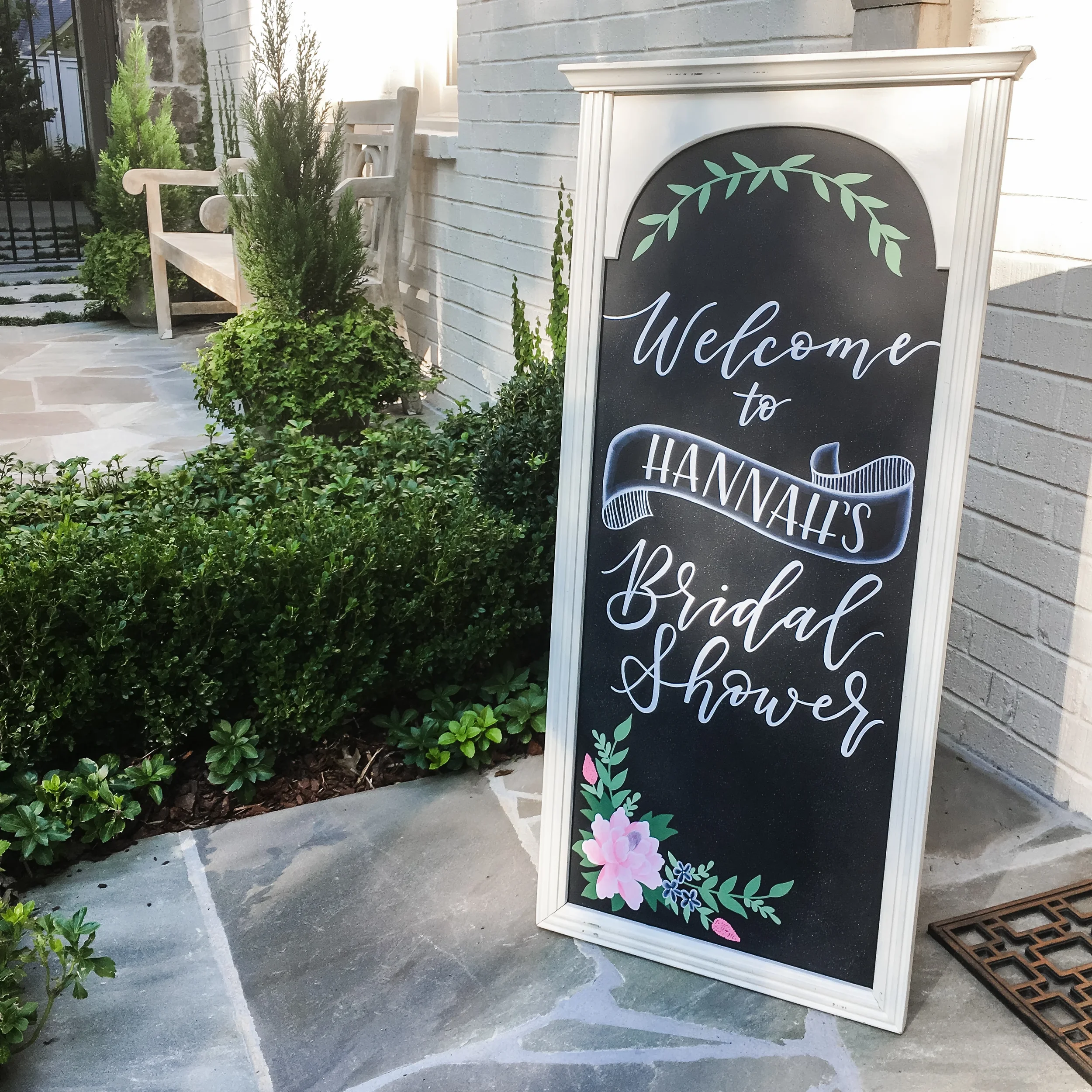 Custom hand-lettered bridal shower chalkboard welcome sign with hand-painted blush flowers and greenery.