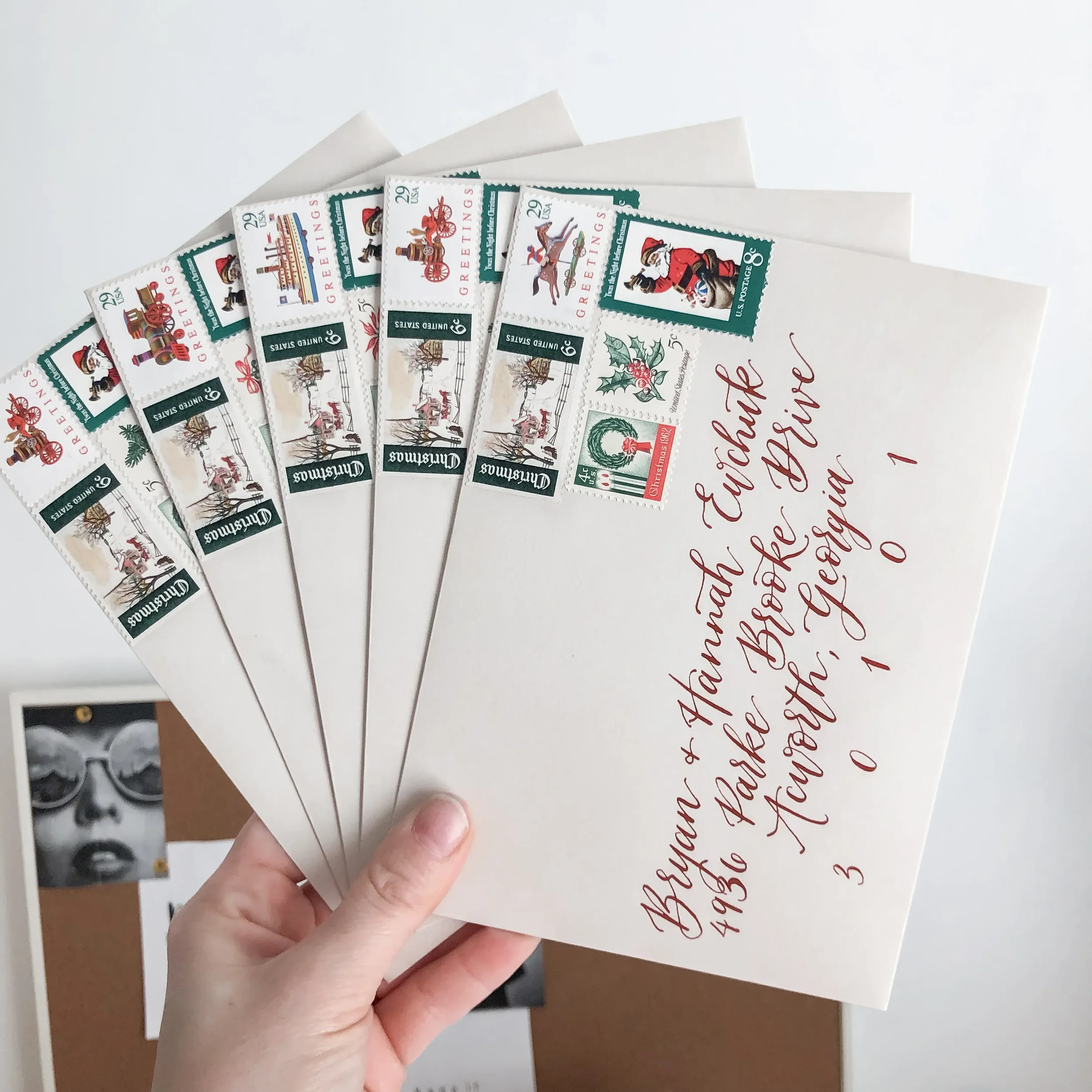 Taupe envelopes with dark red calligraphy address and assorted vintage Christmas stamps for Christmas cards.
