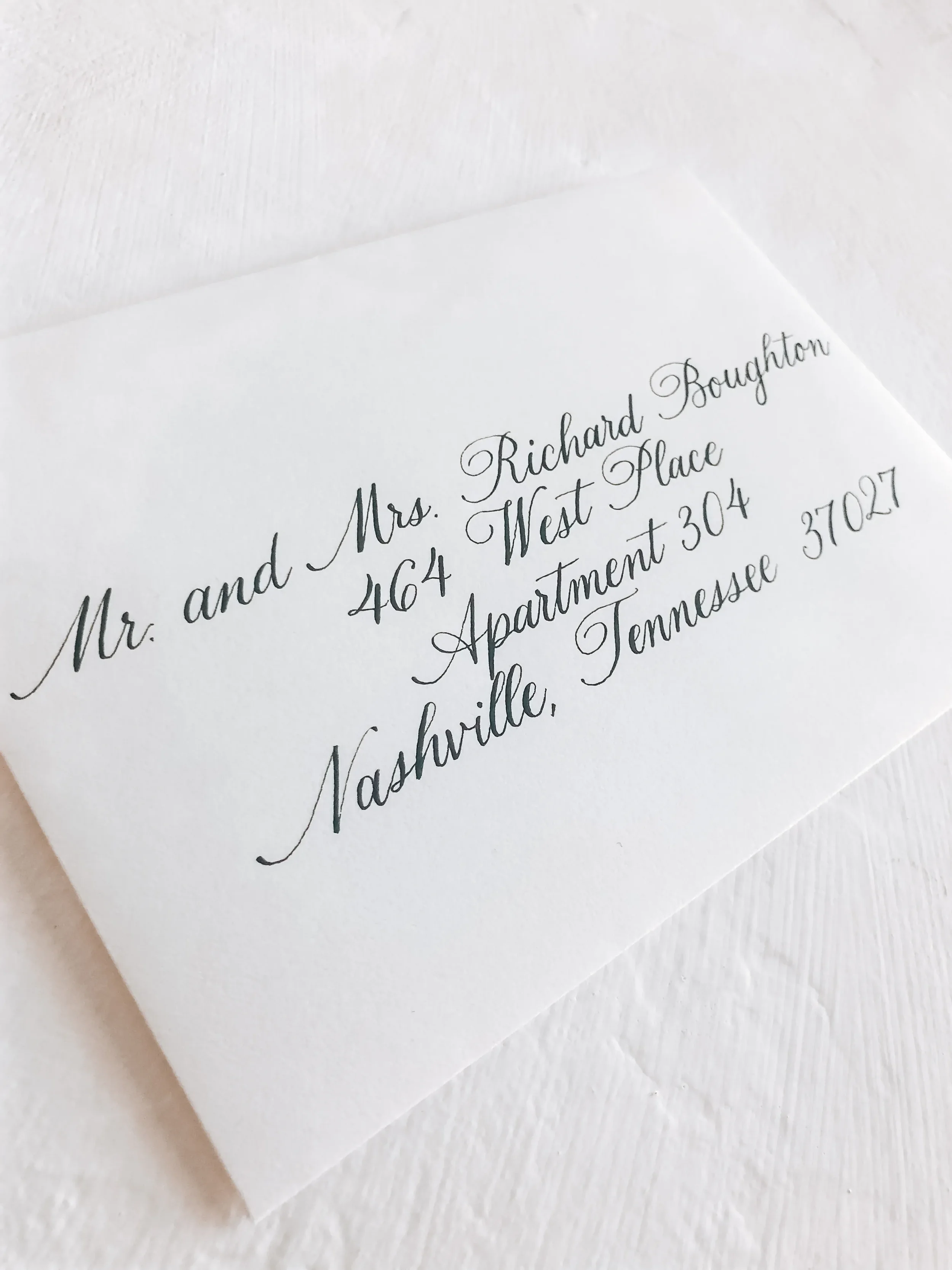 Traditional black ink calligraphy on a clean white wedding guest envelope.