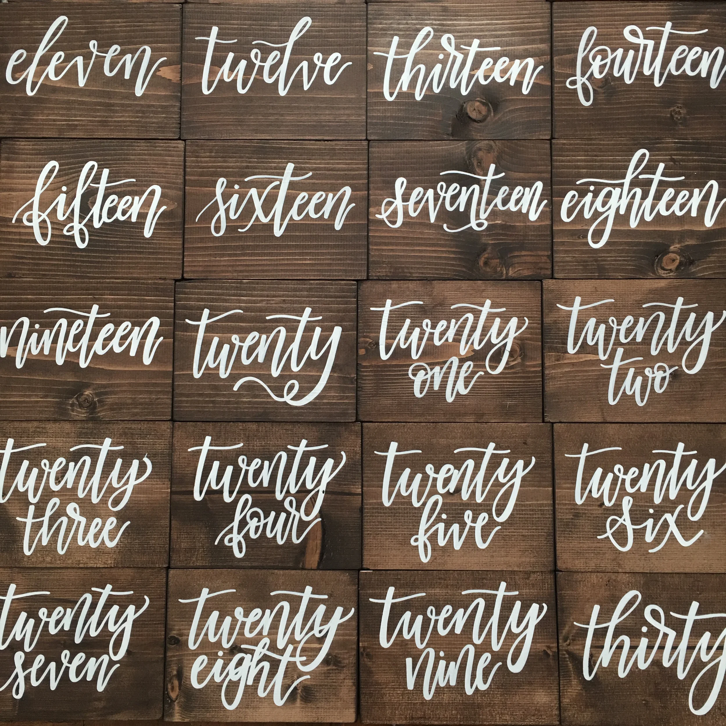 Dark stained wood block table numbers in white script lettering.