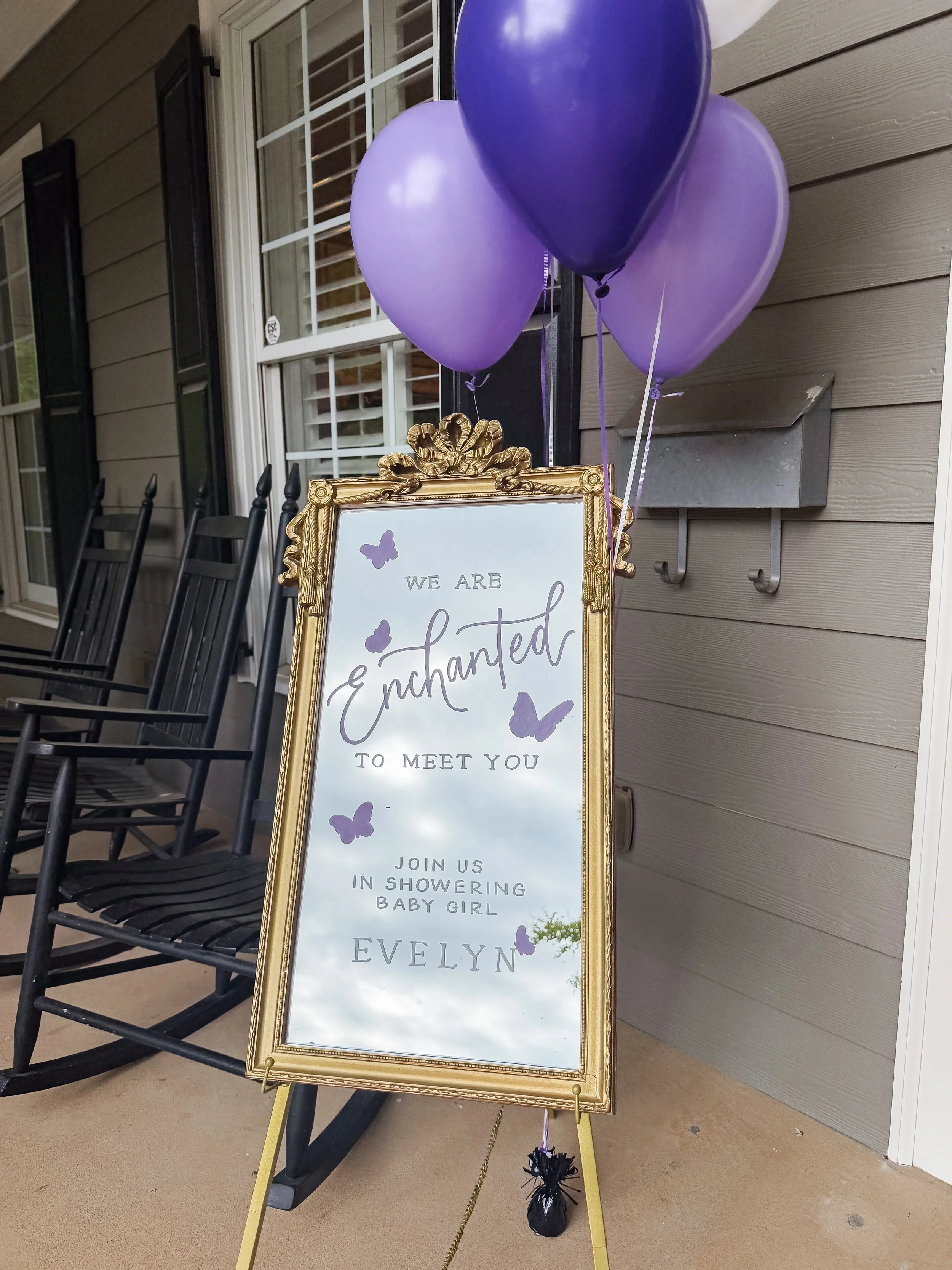 Welcome guests in fairytale style with an ornate gold mirror easel sign. Decorated with custom purple calligraphy, delicate butterfly decals, and a matching balloon cluster, this vintage glass sign brings magical charm to baby showers, bridal showers