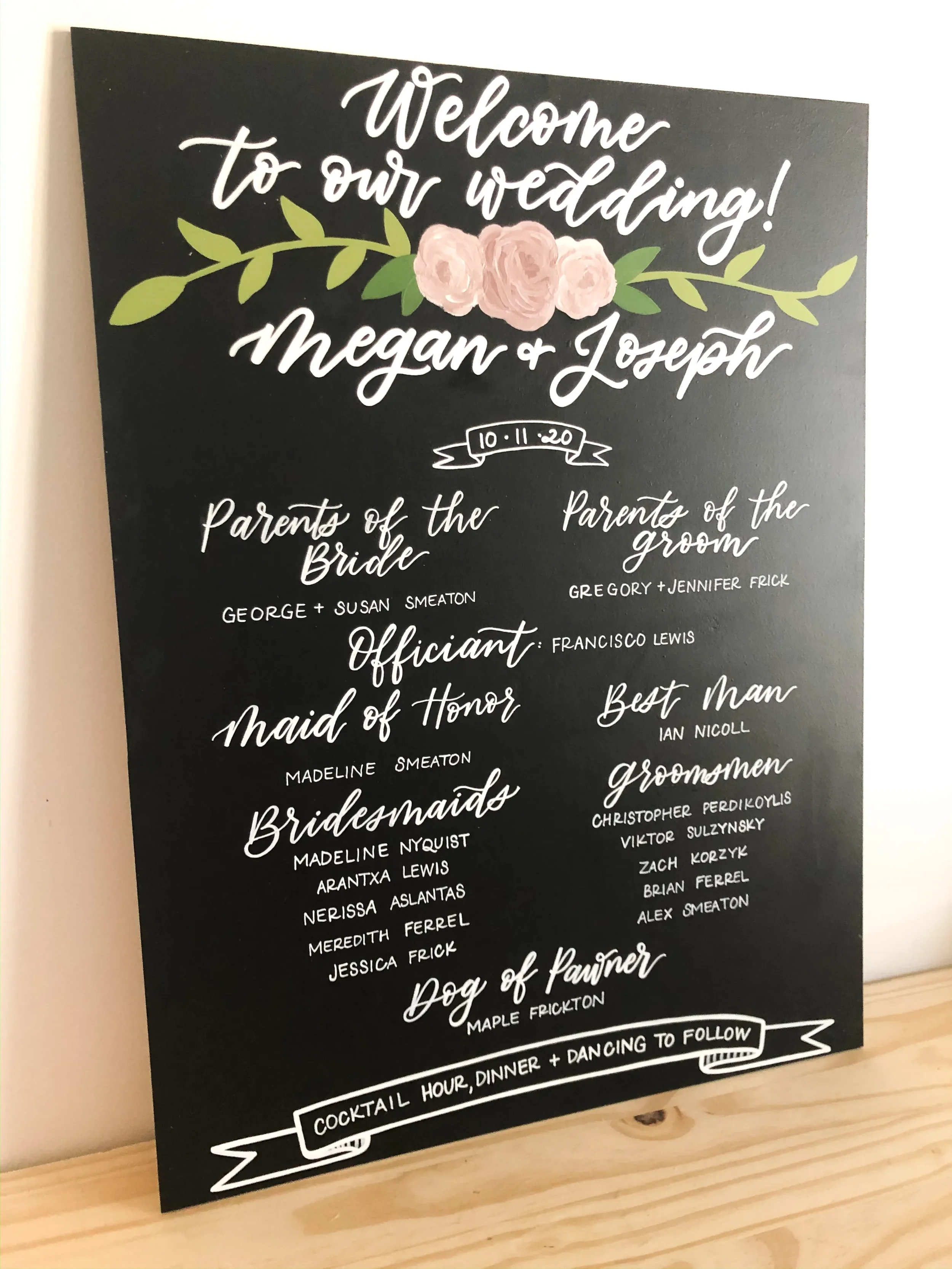 Large chalkboard wedding welcome sign detailing the bridal party names with pink floral chalk art.