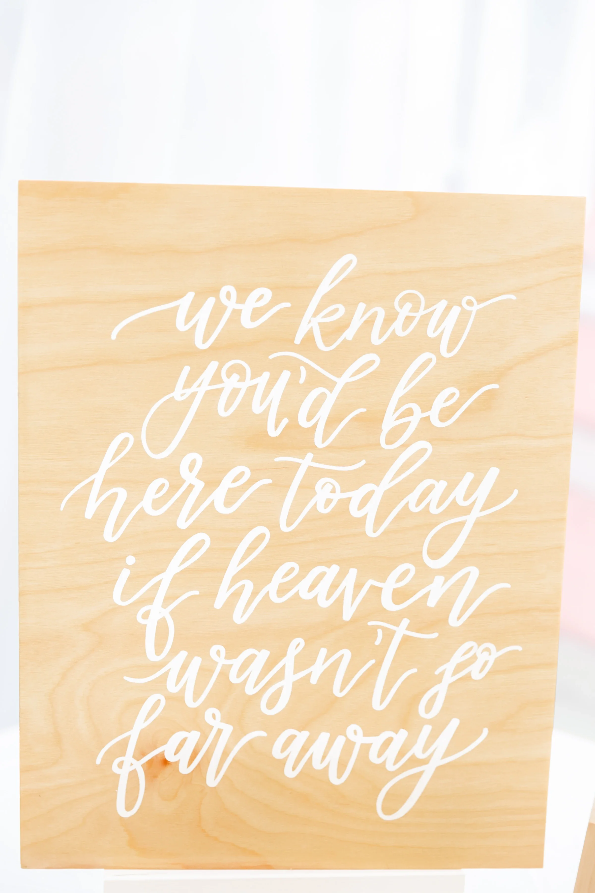 Natural wood board written in white calligraphy: "We know you'd be here today if heaven wasn't so far away."