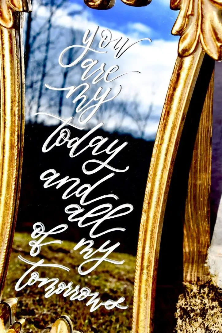 Enhance your venue decor with a romantic custom calligraphed mirror sign. Framed in a carved vintage gold finish, this narrow mirror features the romantic quote "You are my today and all of my tomorrows" written in fluid white ink—ideal for photo bac