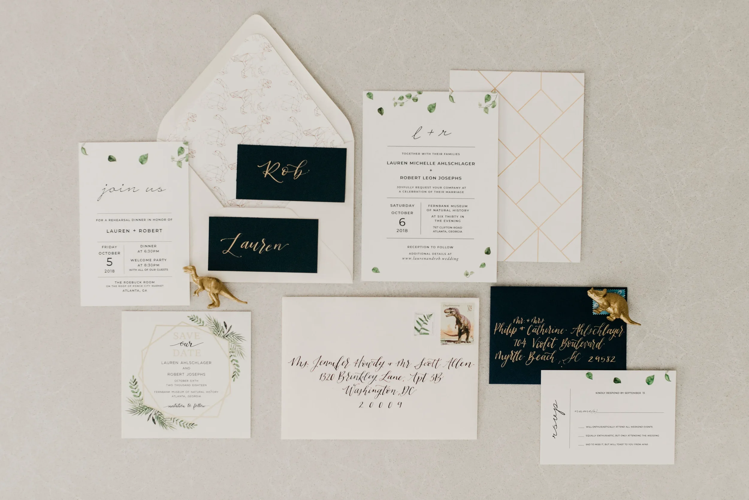 Minimalist dinosaur wedding invitation card with simple green eucalyptus leaves and a geometric gold patterned backing.