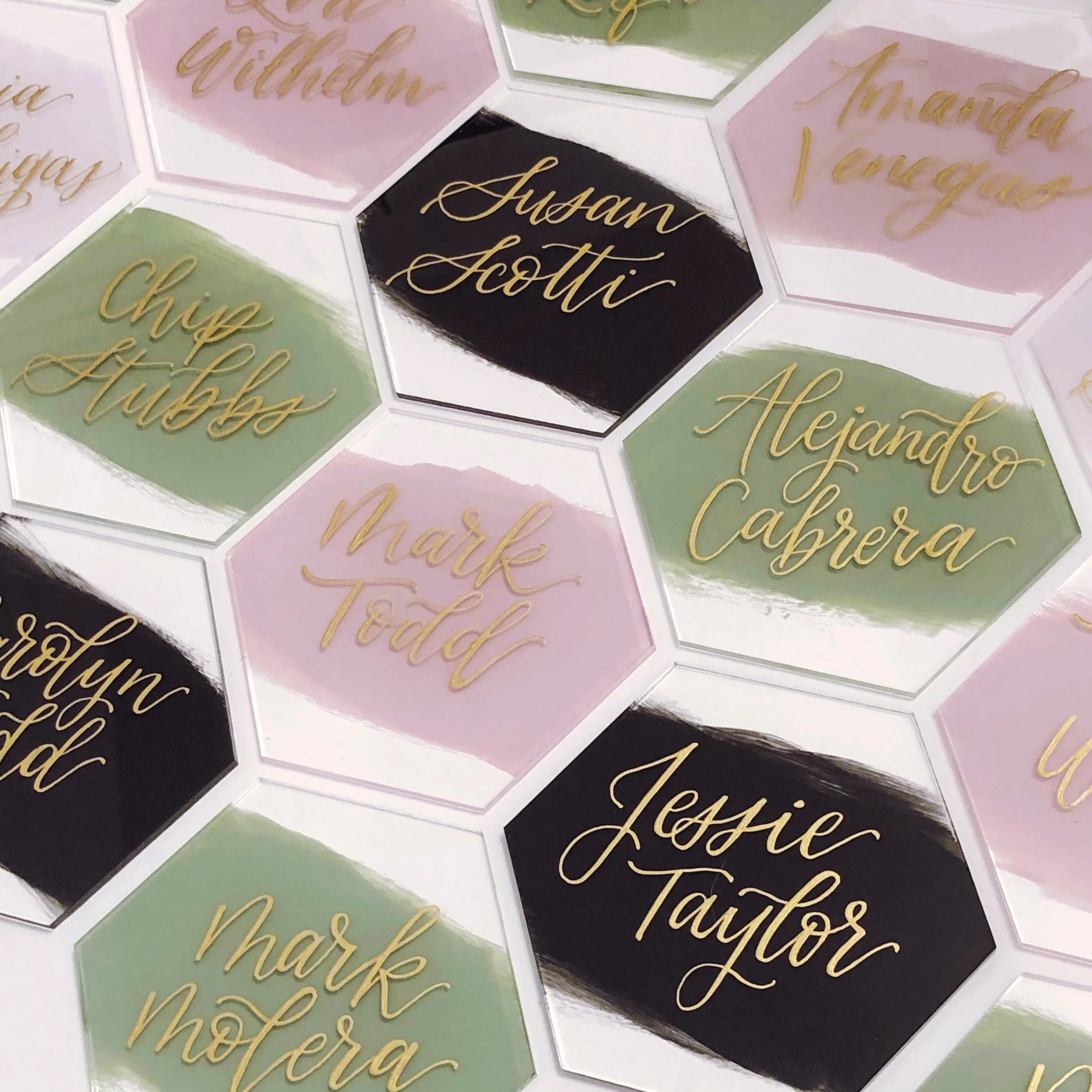 Modern painted back acrylic hexagon tile wedding escort cards featuring reflective metallic gold hand-lettering.