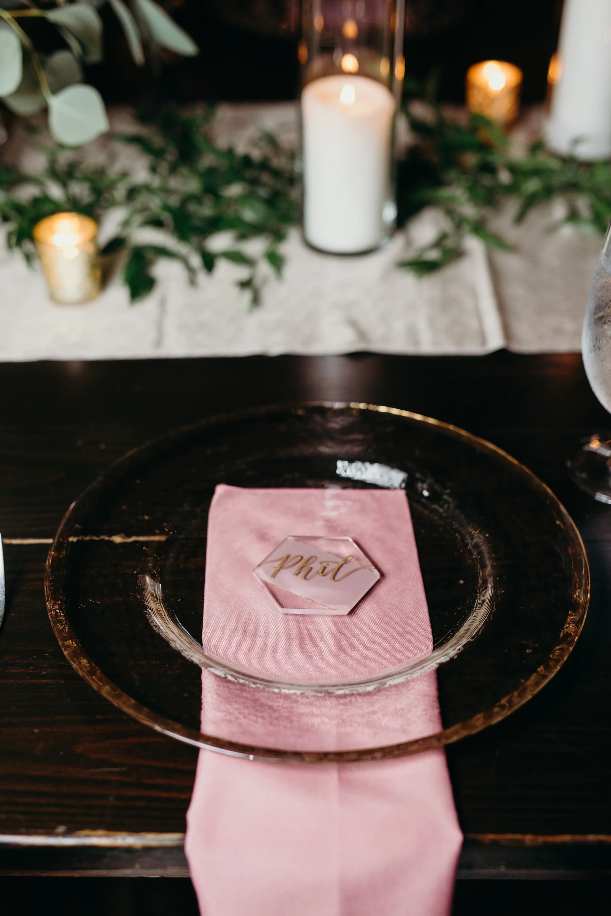 Overhead view of a geometric acrylic wedding place card on a mauve linen napkin.
