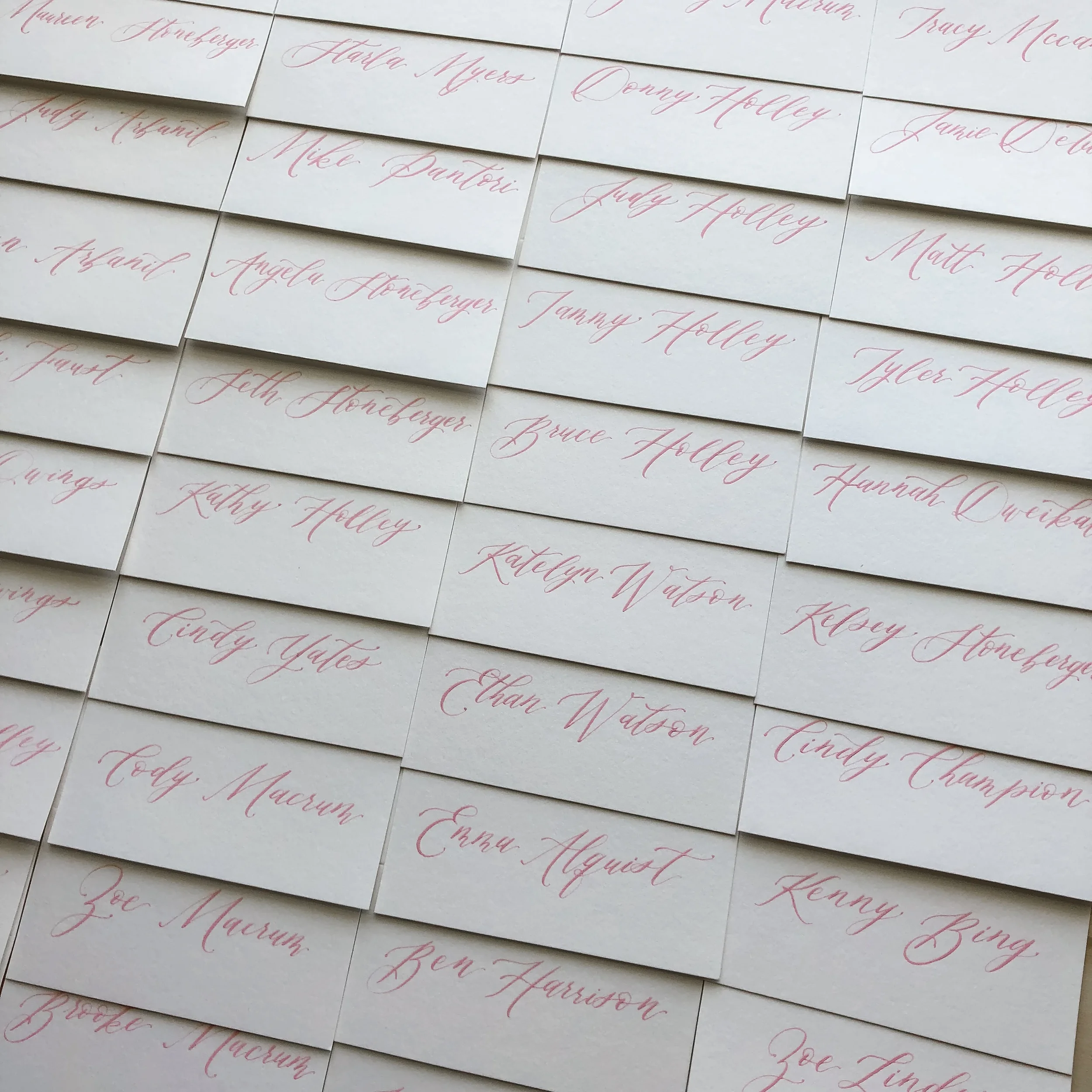 Bring a soft, cohesive splash of color to your seating presentation with an array of hand-lettered escort cards written in a romantic blush pink calligraphy ink.