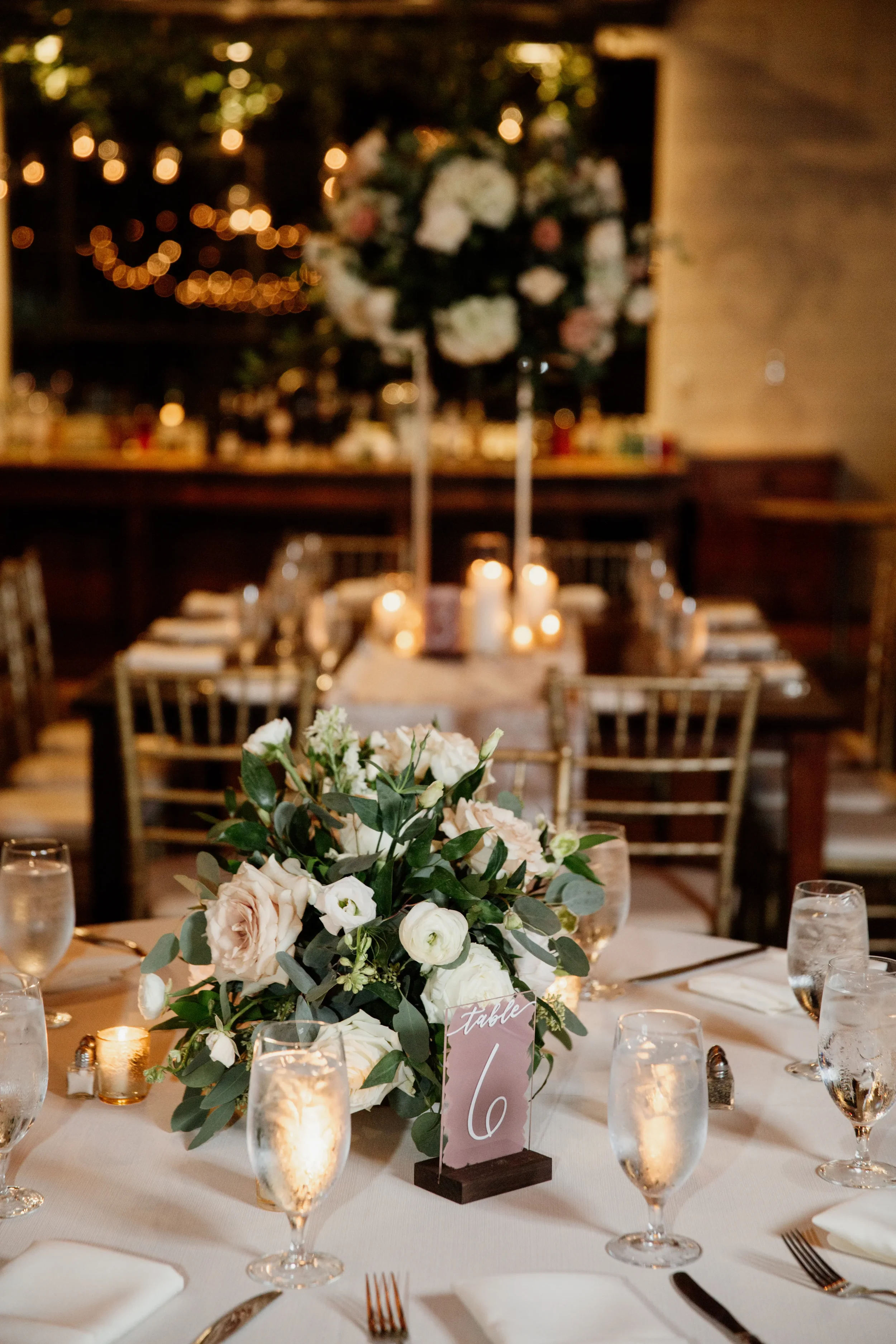 Mauve painted back acrylic wedding table number sign styled with white and blush roses.