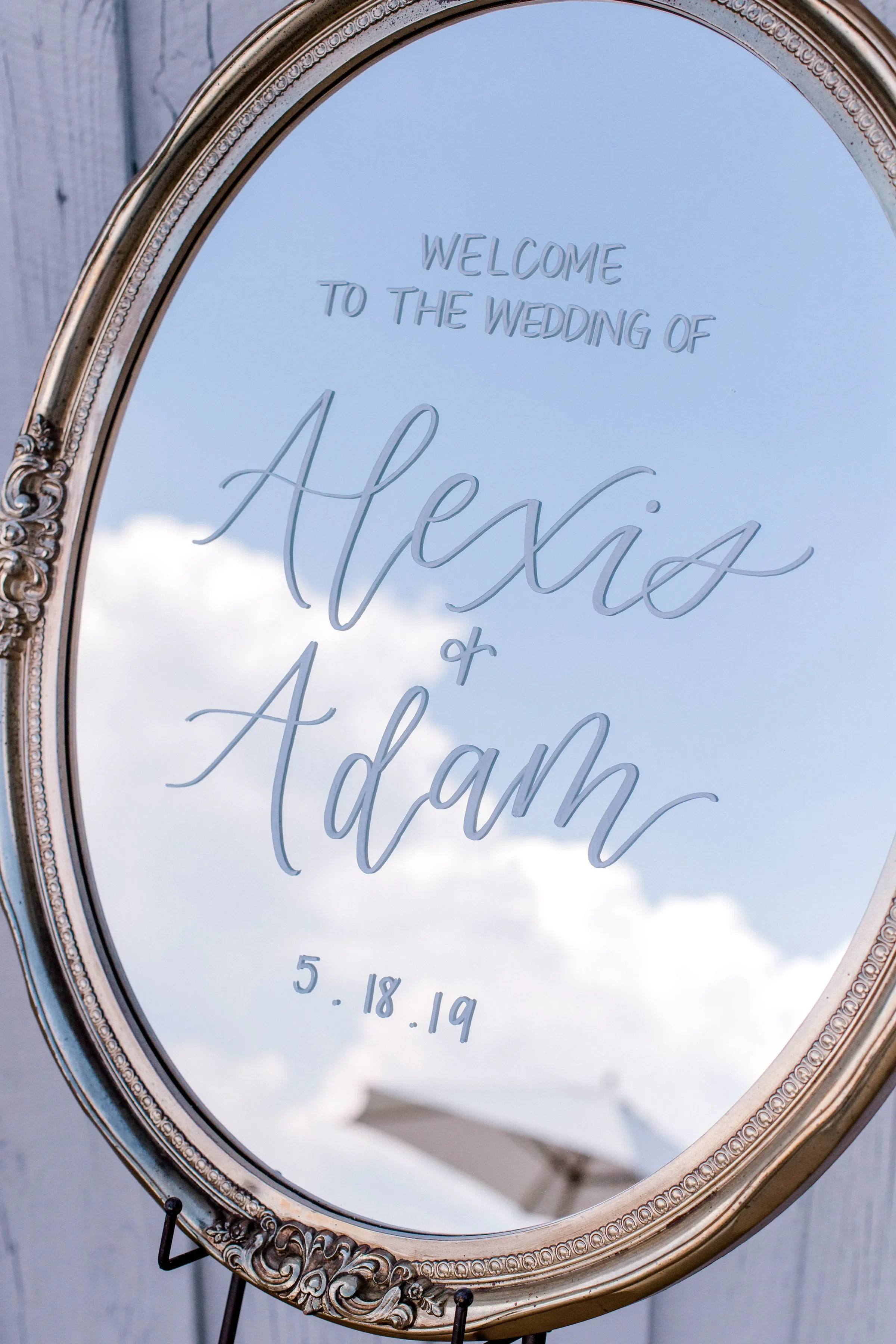 Welcome your guests with a custom mirror welcome sign featuring hand-lettered white calligraphy. Staged on an easel, this classic welcome sign offers perfect design inspiration for a romantic estate, garden, or rustic elegant wedding theme.