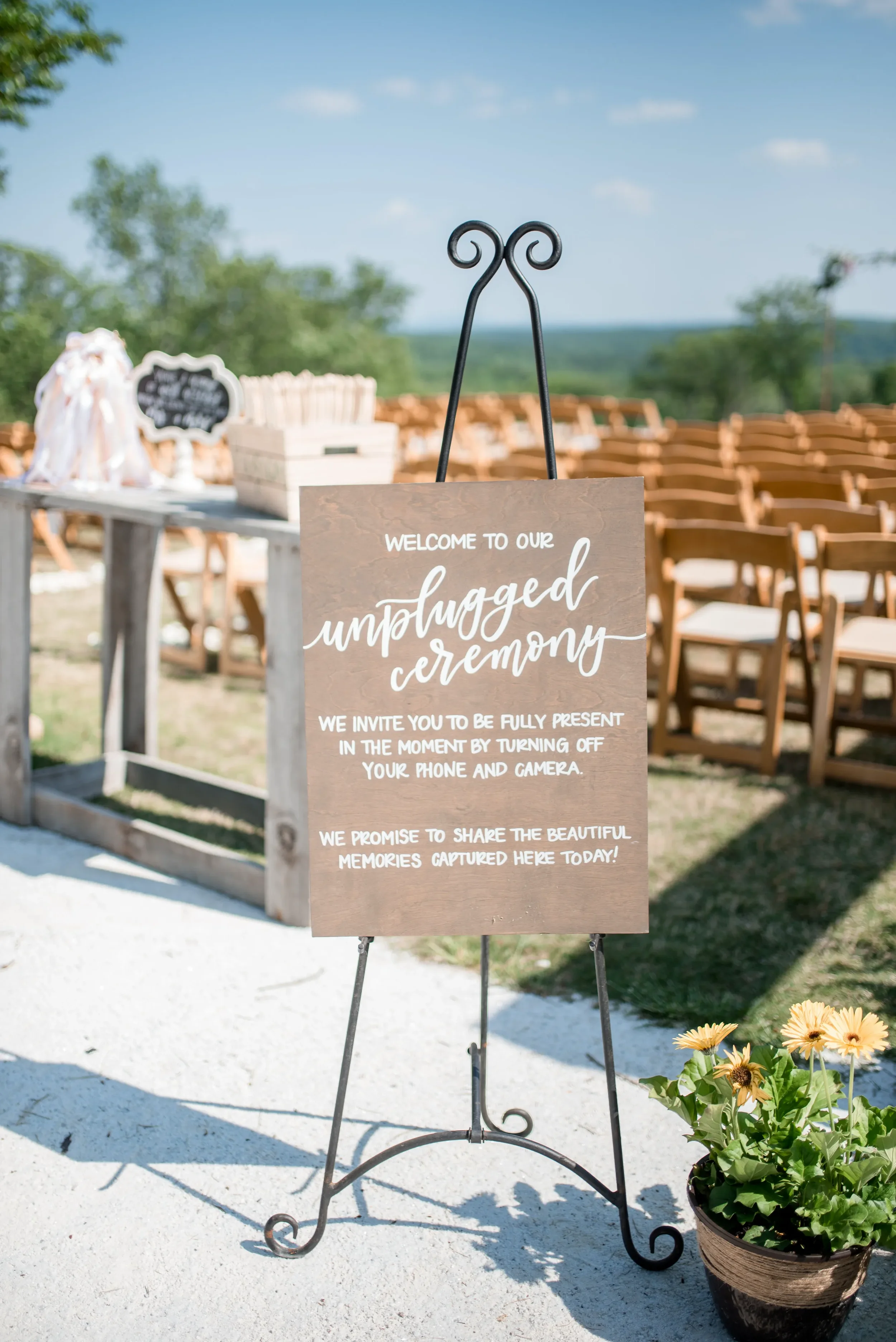 Hand-lettered wooden unplugged ceremony wedding sign displayed on a wrought-iron easel at an outdoor Georgia ceremony.
