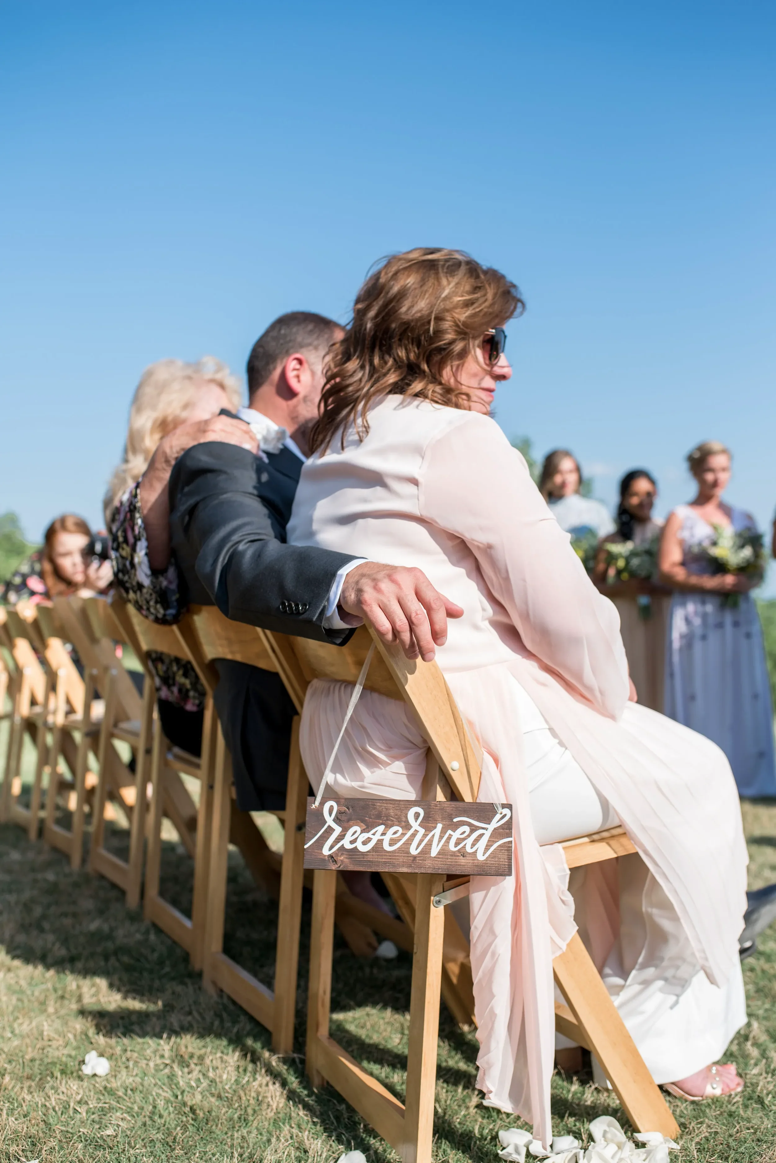 Hand lettered wooden reserved chair sign with white calligraphy for outdoor Georgia wedding.
