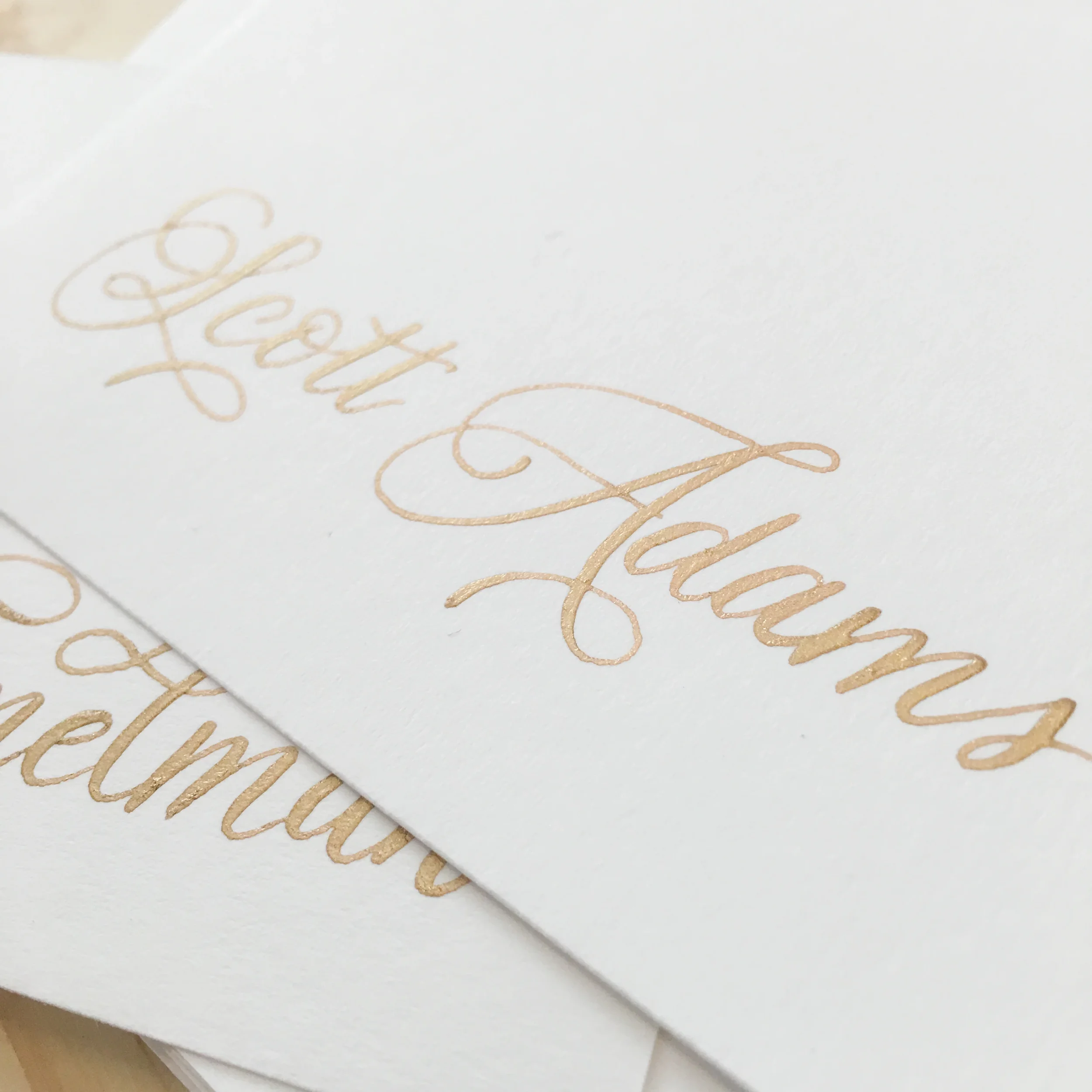 White tented place cards with traditional gold ink calligraphy.