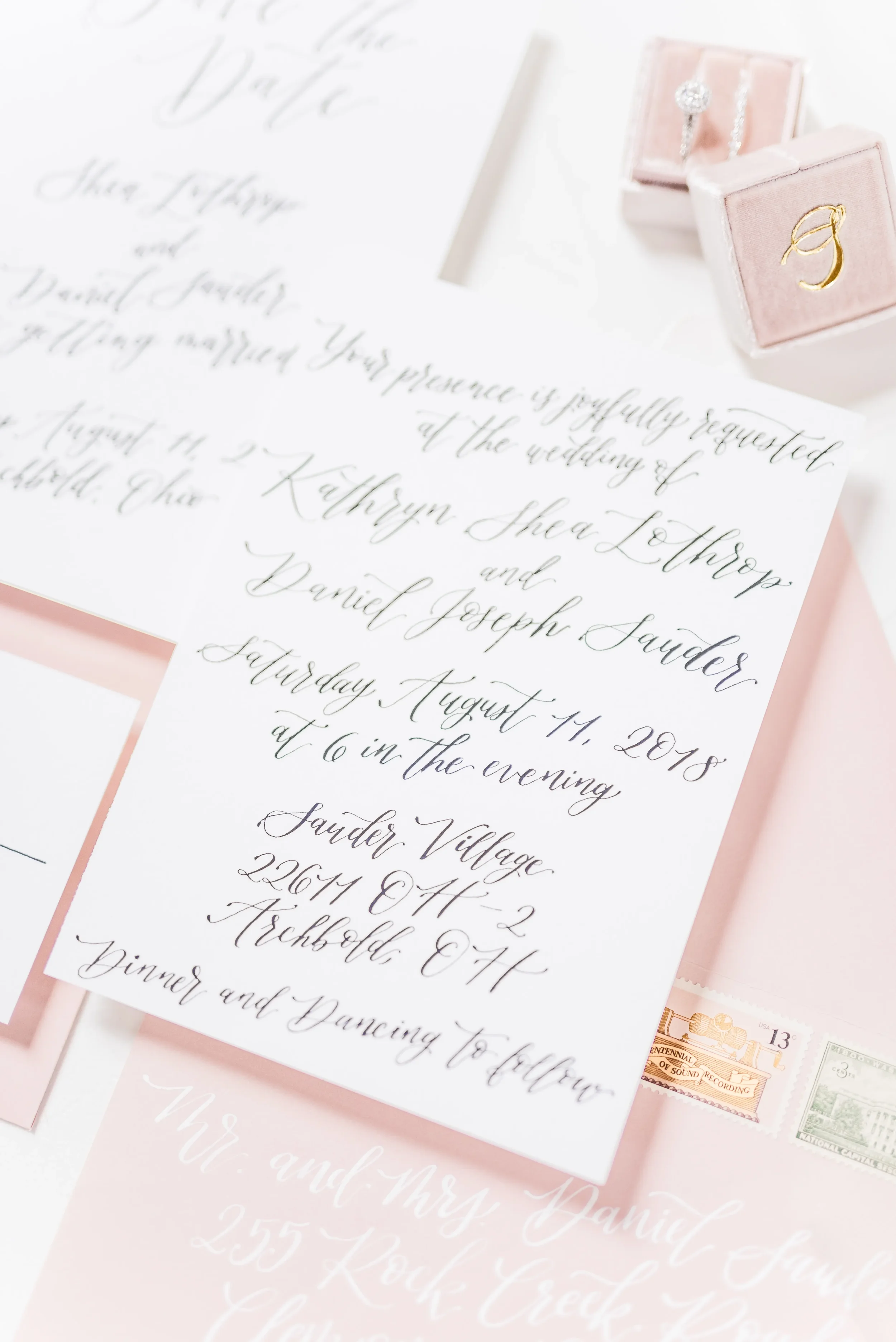 Fine art wedding stationery flat lay featuring custom cursive script and matching pink envelopes.