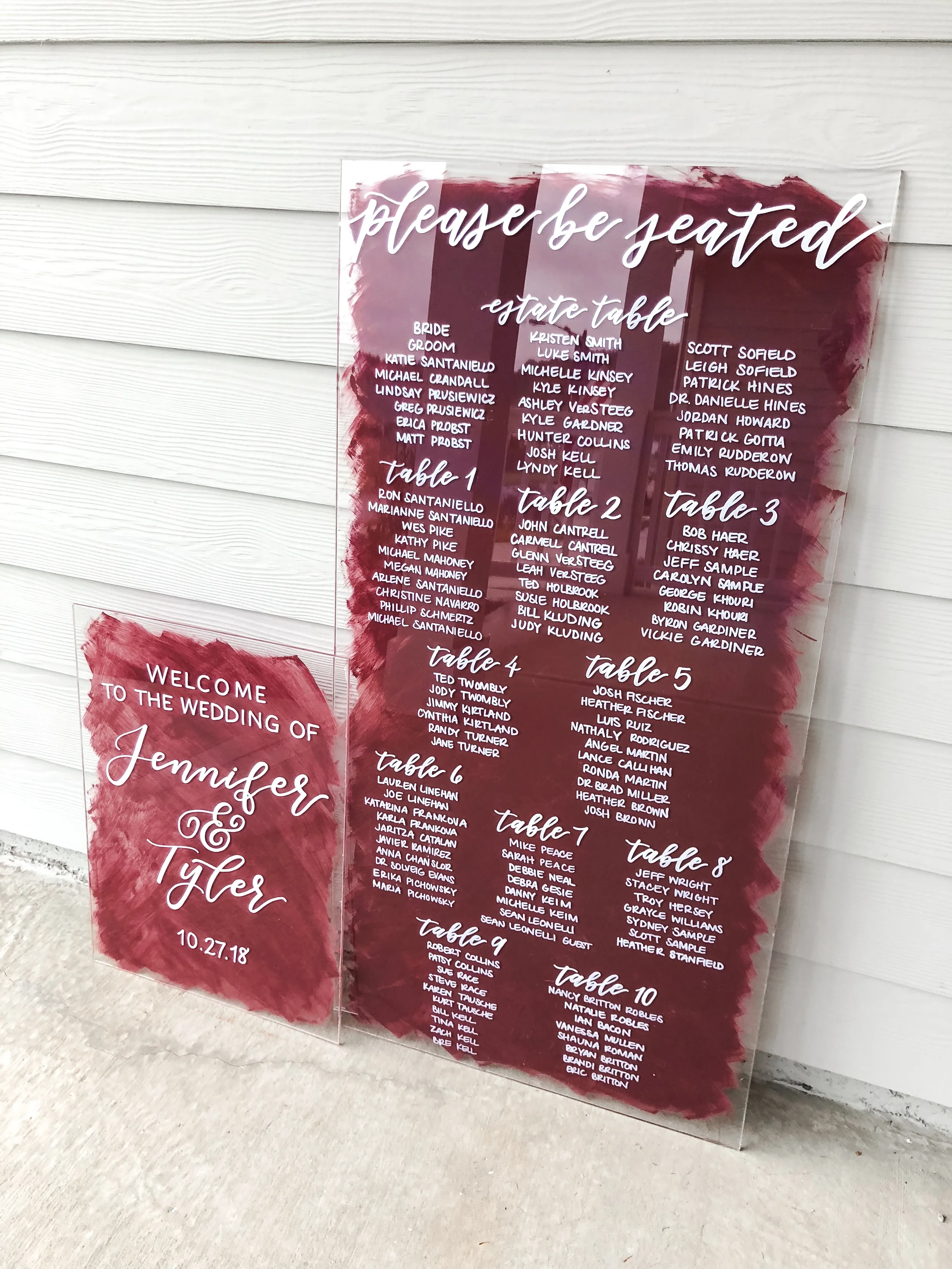 Large burgundy painted-back acrylic with white lettering wedding seating chart and welcome sign.