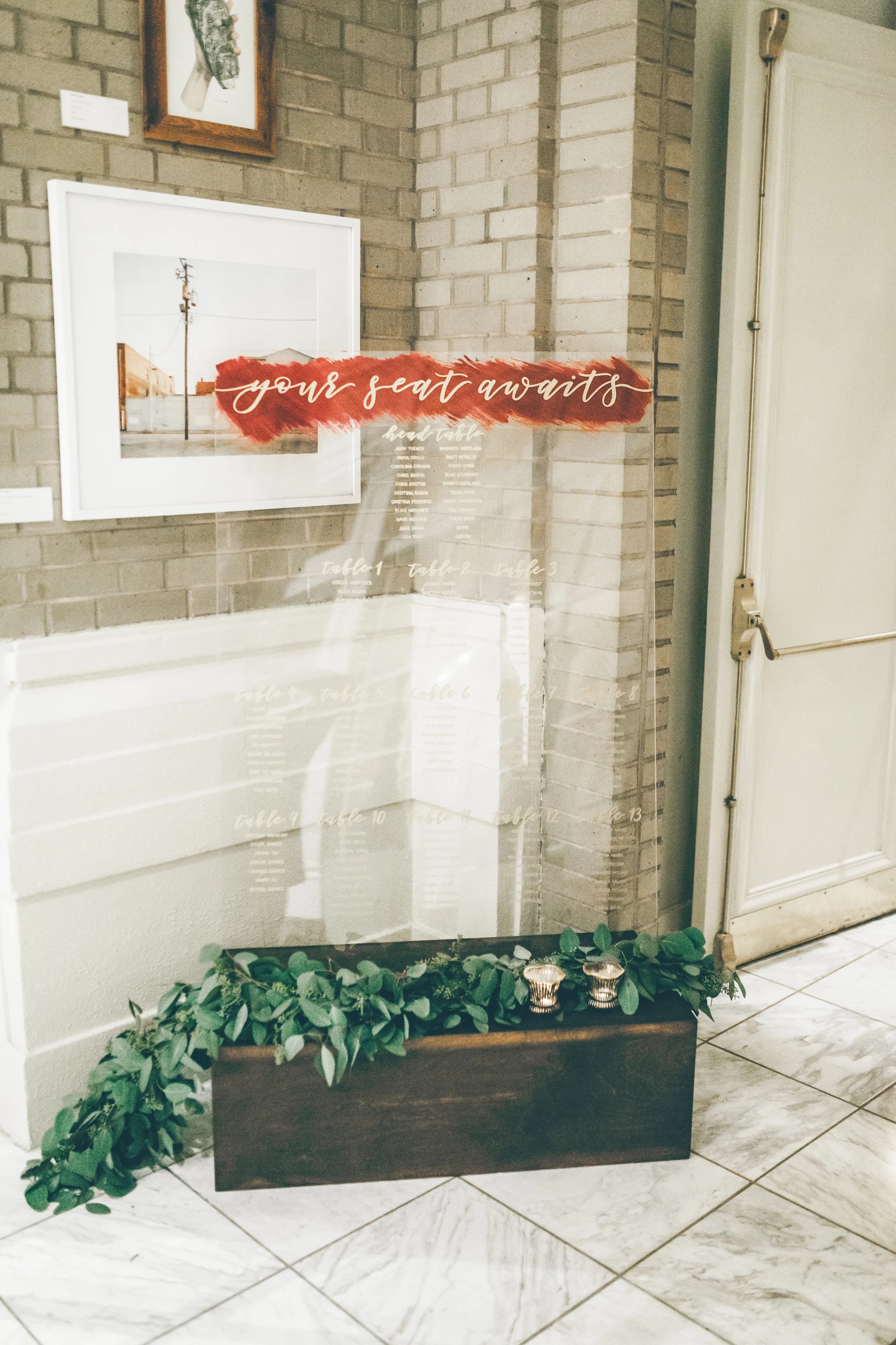 Move away from traditional paper seating walls with a large, freestanding clear acrylic wedding seating chart. Slotted into a custom dark wood base, this striking transparent directory adds a modern, fine-art element to an outdoor garden or pavilion 