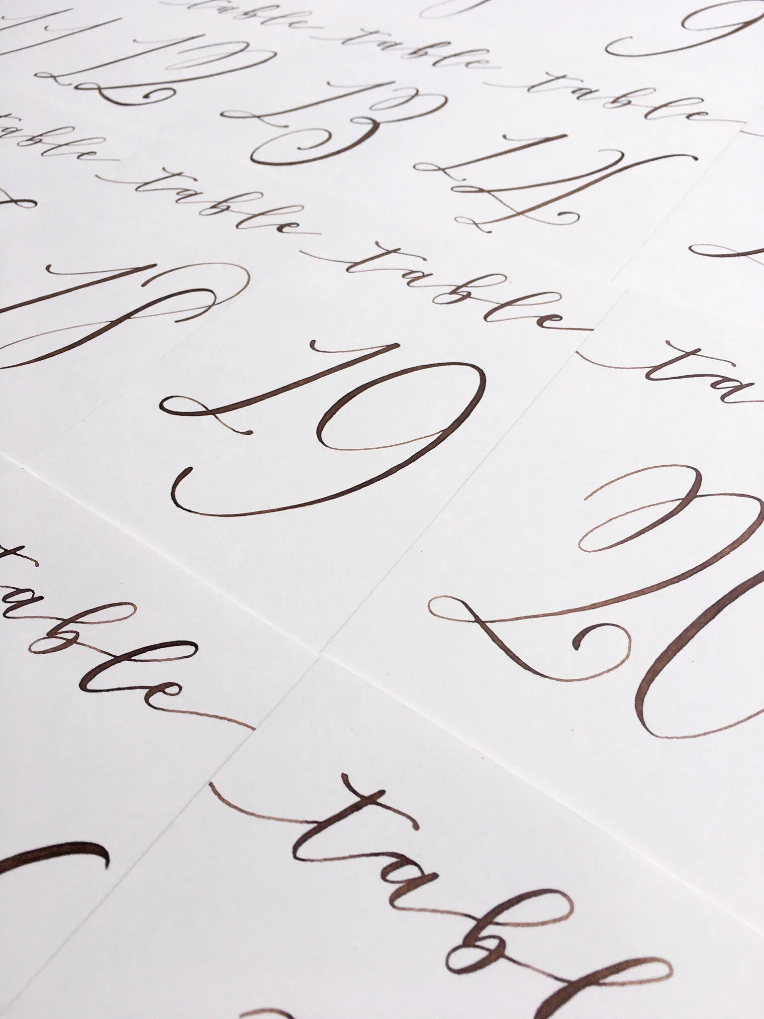 Elegant calligraphed wedding table numbers printed on clean white paper.