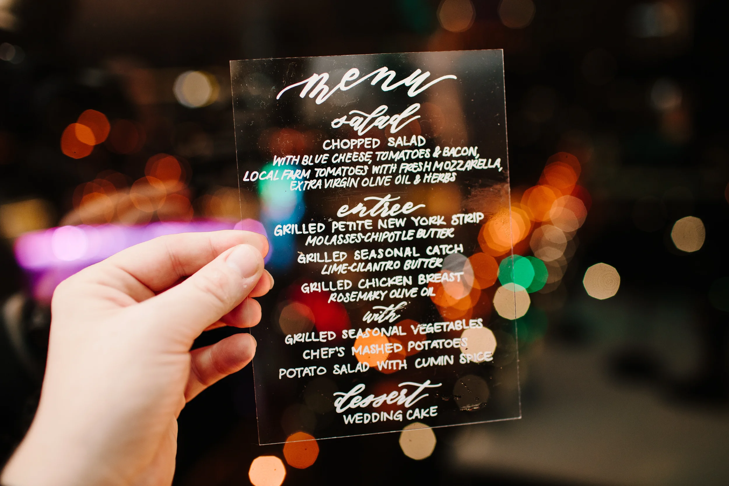 Clear acrylic wedding menu sign with white script calligraphy at an Atlanta city reception.