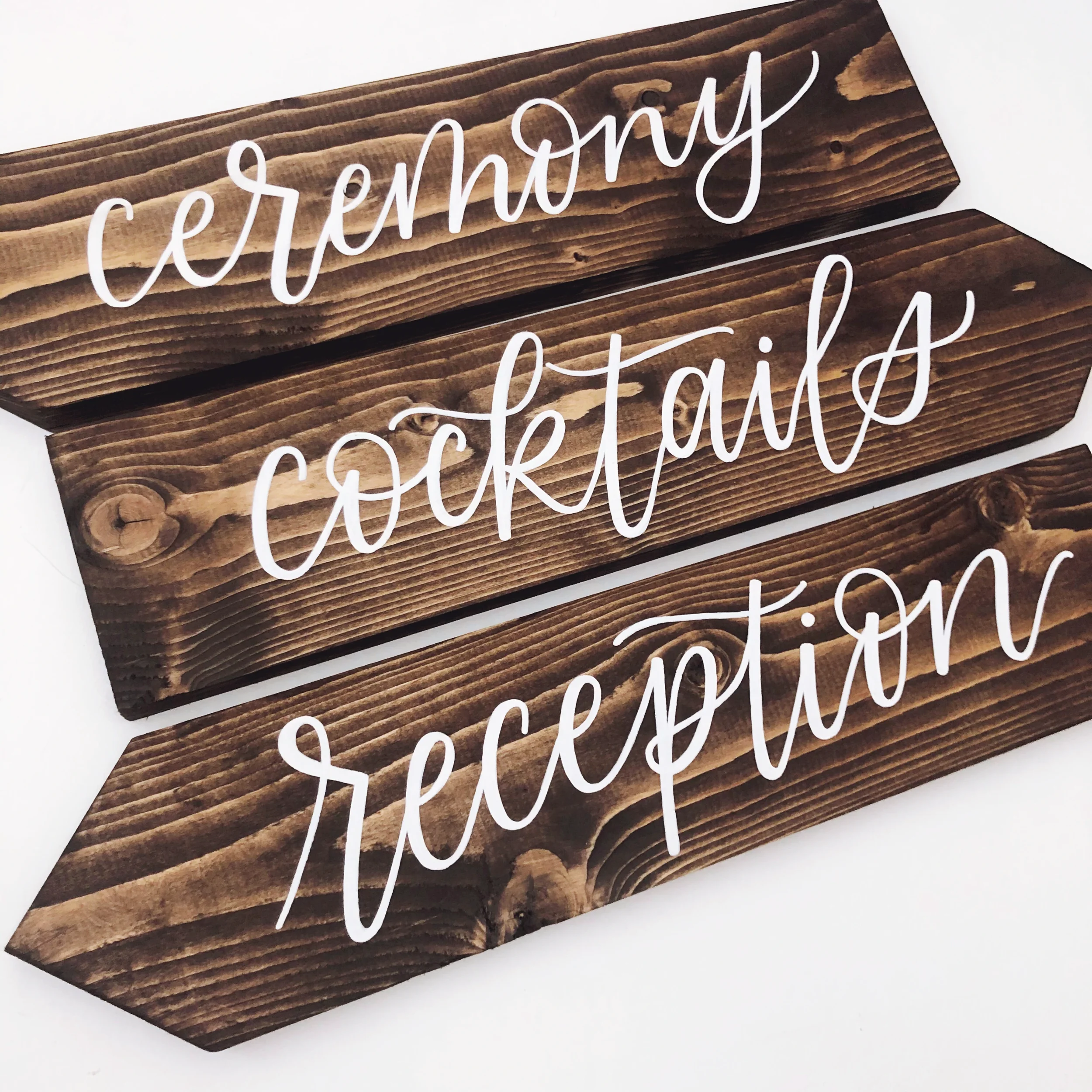 Direct your guests effortlessly across your event space with a rustic wooden directional signpost. Featuring hand-lettered arrows pointing to the ceremony, reception, and cocktail hour, this wooden wayfinding sign is ideal for outdoor, farm, or fores