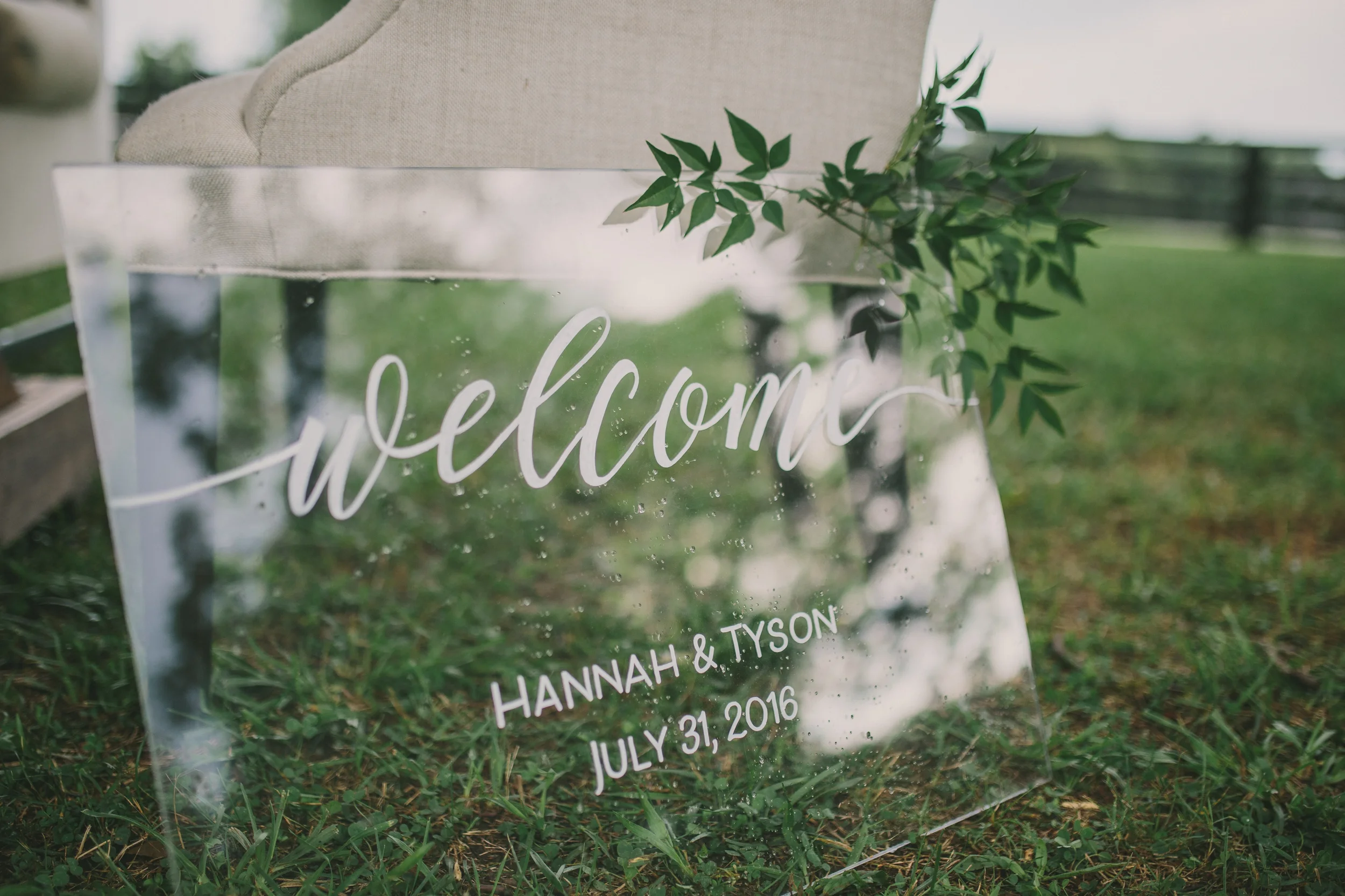 Clear acrylic wedding welcome sign with fine white script calligraphy.
