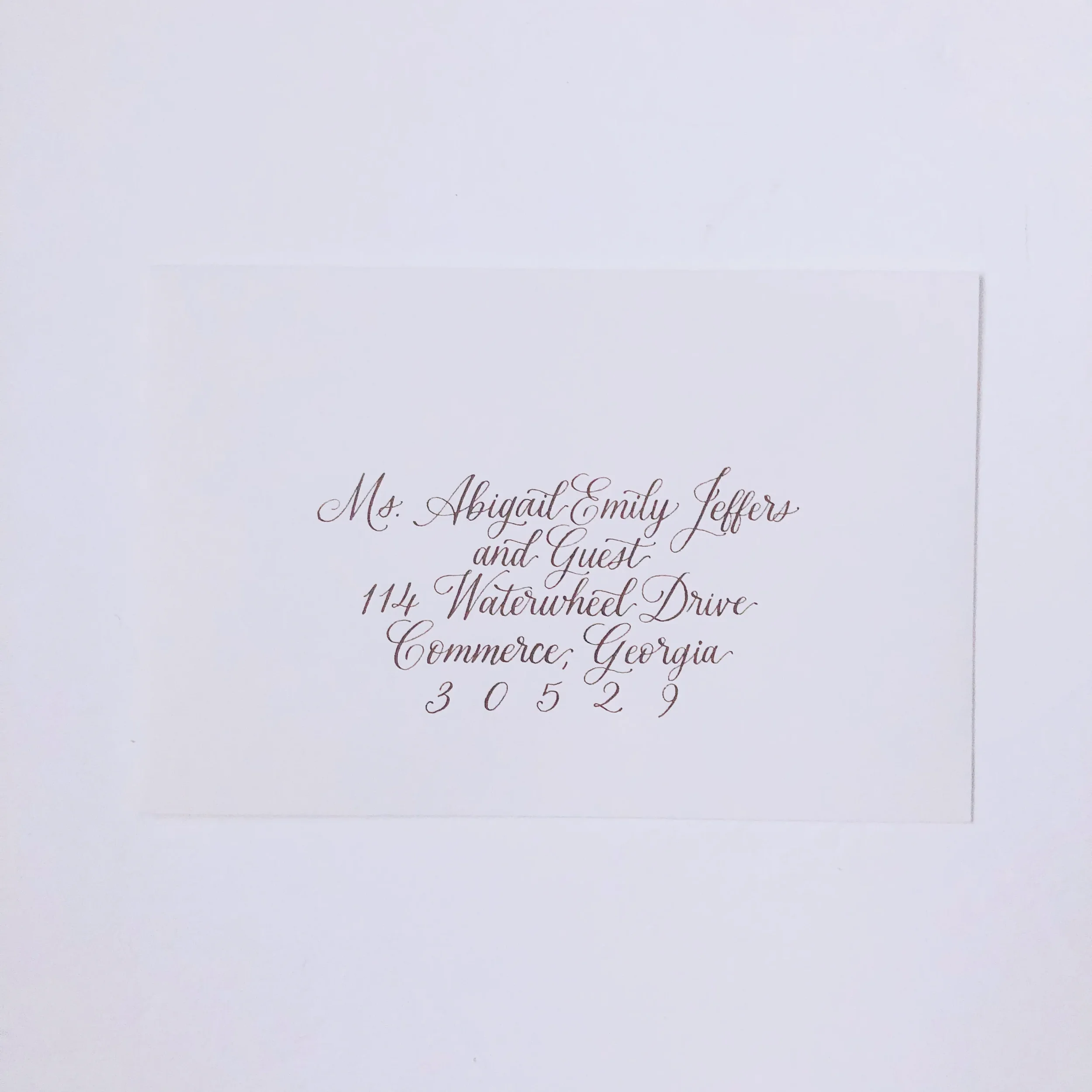 Professional wedding envelope calligraphy featuring uniform, formal cursive handwriting in walnut ink on a crisp white envelope.