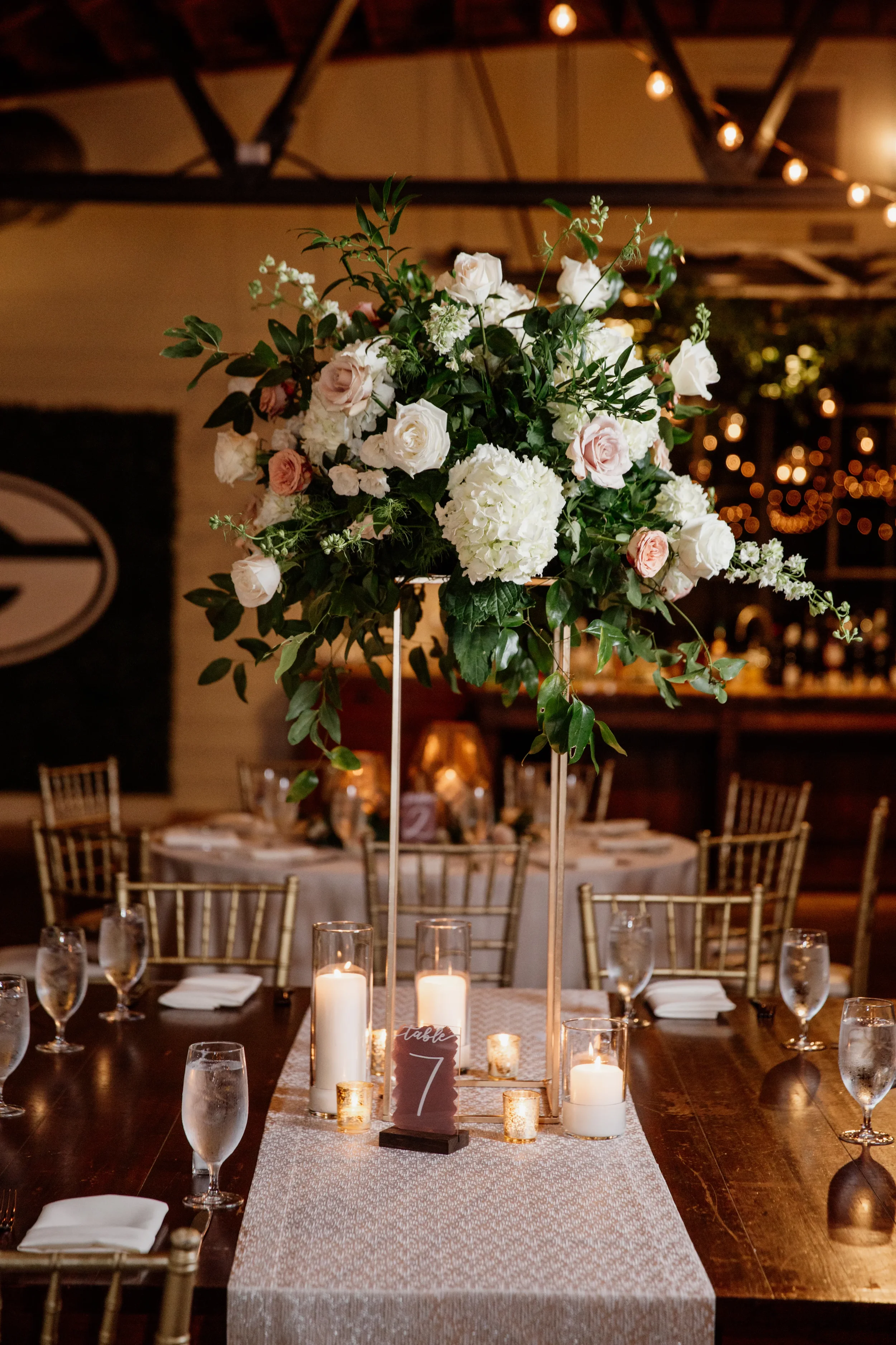 Mauve painted back acrylic wedding table number sign styled with white and blush roses.