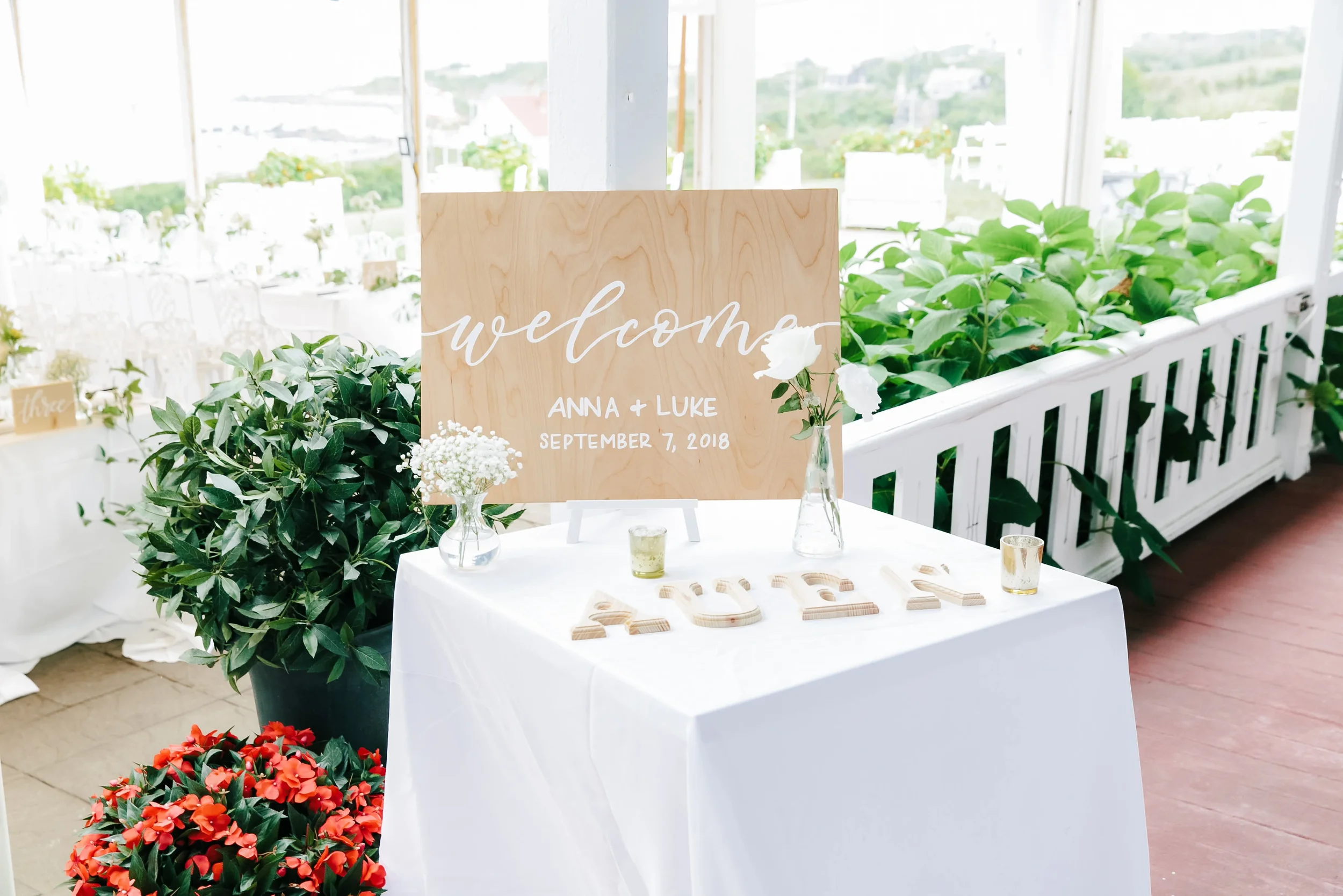 Rustic wooden welcome board featuring modern calligraphy script and event date displayed outdoors.