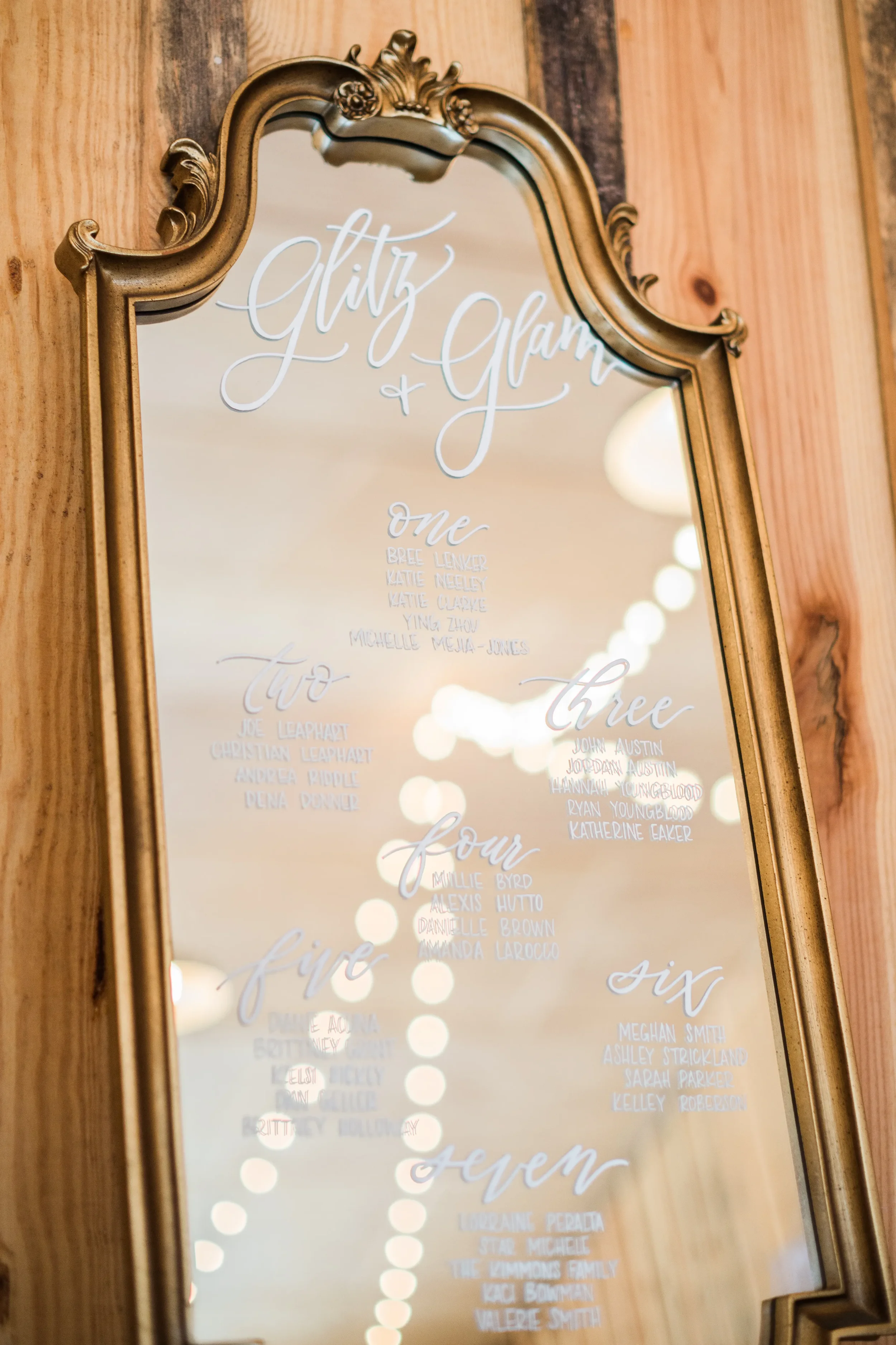 Close up of vintage gold mirror seating display with white hand-lettered guest names for any wedding or event.