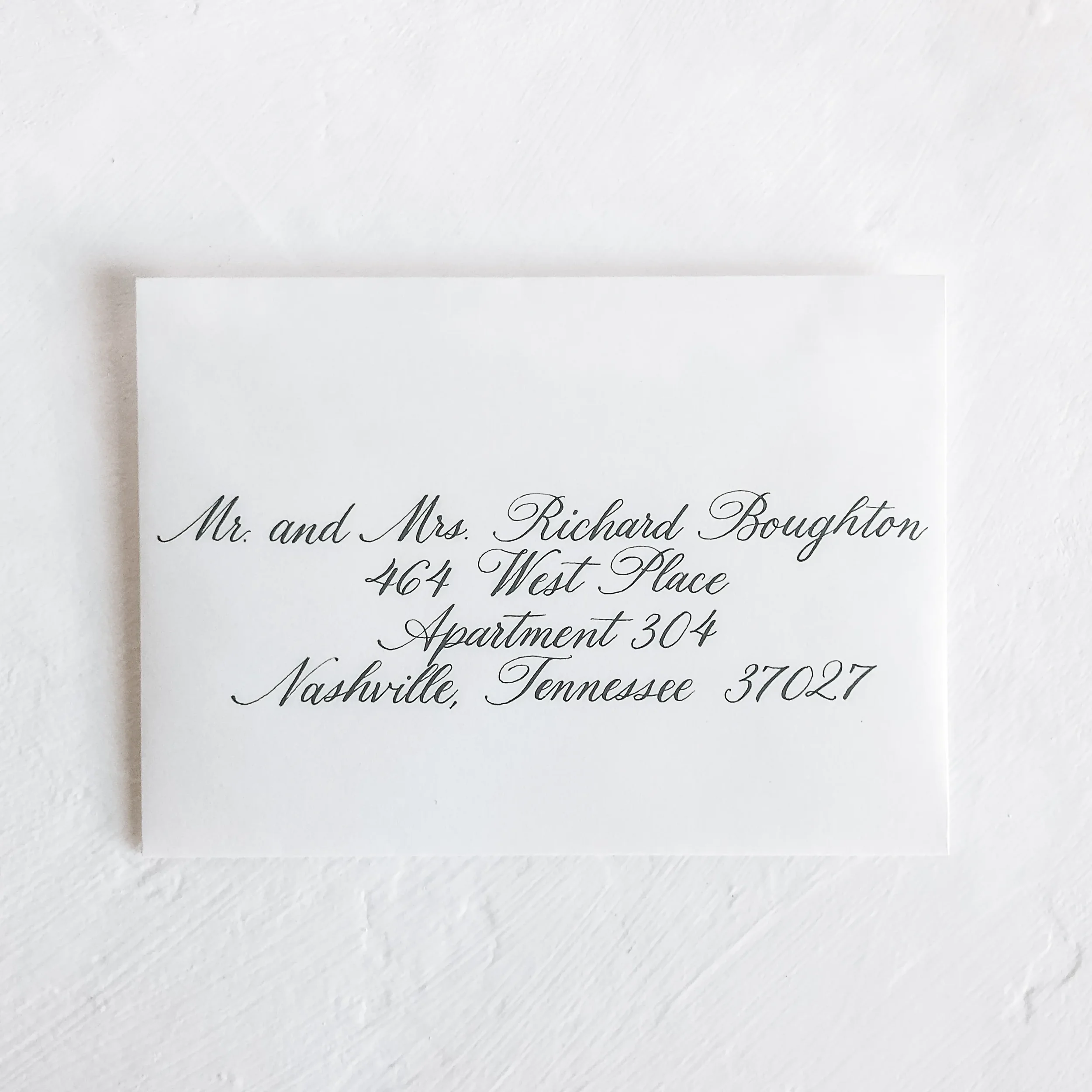 Meticulous cursive script envelope addressing with a vintage look on textured white cardstock.