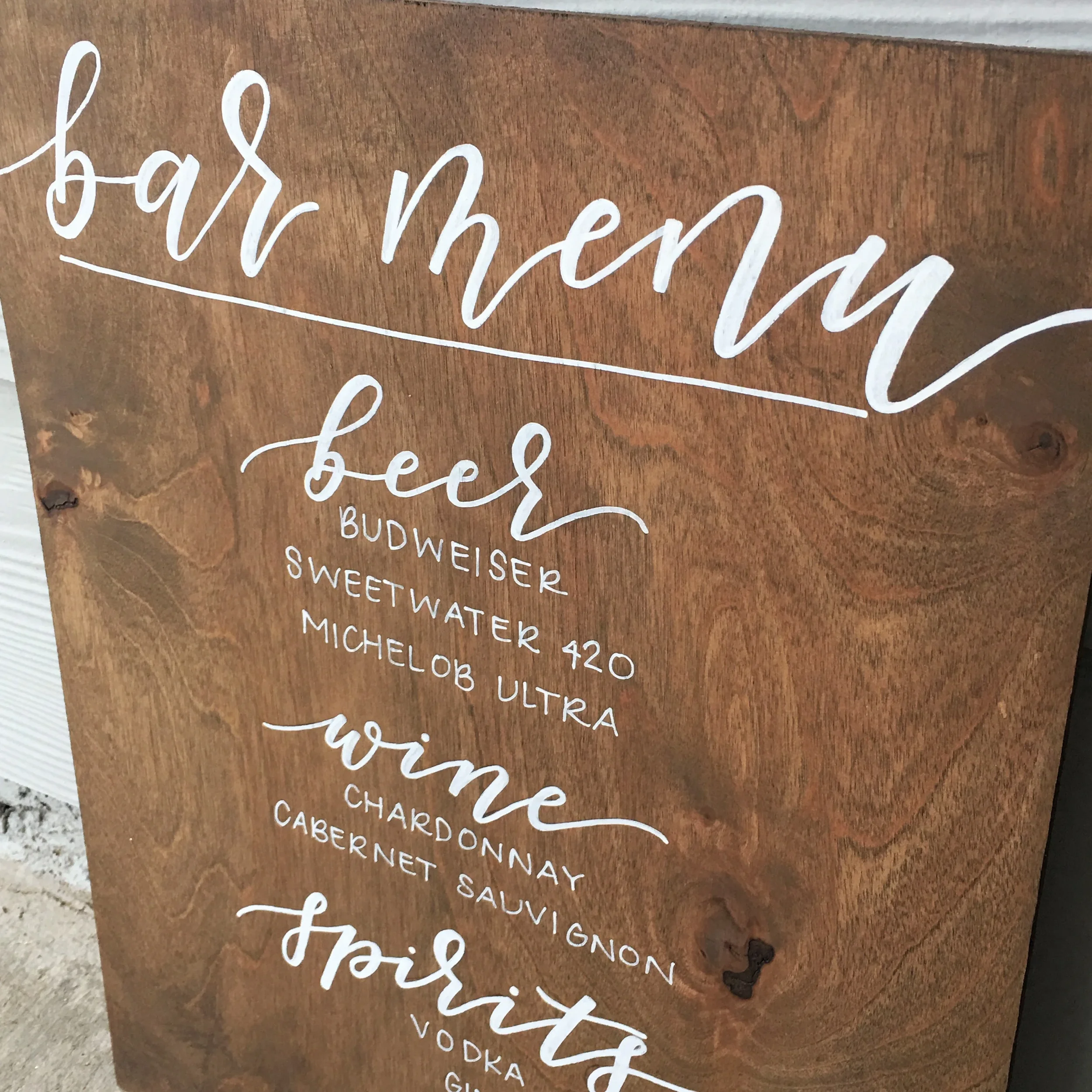 Stained wood bar menu sign listing beer, wine, and spirits options.